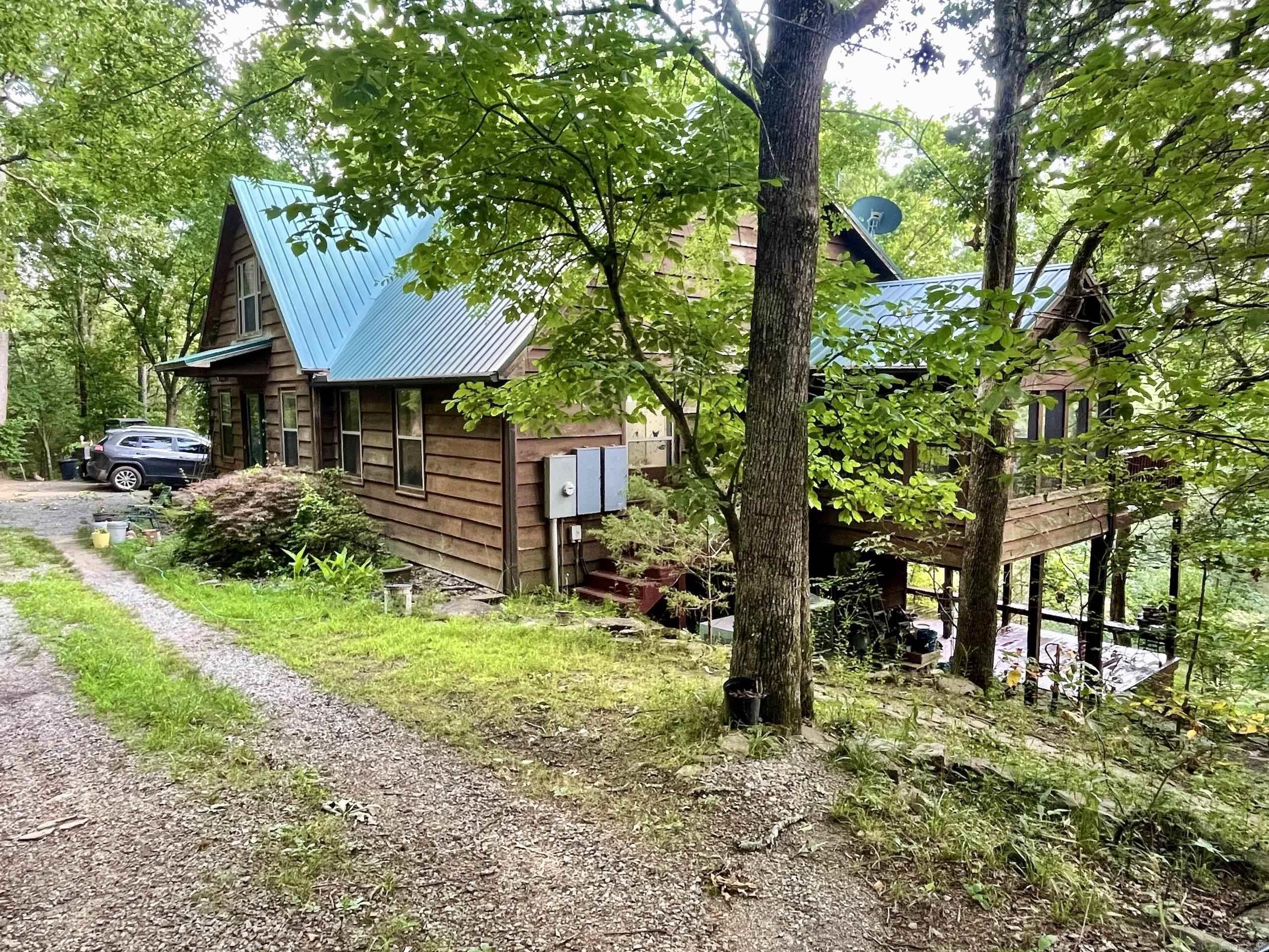 Tucked deep into the forest and nestled along the scenic banks of Cadron Creek, this stunning 3-bedroom, 3-bathroom mountain retreat offers a rare combination of natural beauty, privacy, and comfort. Designed to blend into the landscape, the home is enveloped by towering oaks, hickory, and cedar trees, with over half a mile of Cadron Creek frontage and nearly a full mile of seasonal creeks winding through the property. This thoughtfully crafted home features two separate living areas and a loft. Each living area has its own kitchen and cozy wood-burning fireplace, making it ideal for multi-generational living or hosting guests. This property offers the ultimate in natural seclusion, yet is only minutes from shopping, schools, and hospitals. Whether you're seeking a quiet primary residence, an inspiring retreat, or a one-of-a-kind family legacy property, this Cadron Creek hideaway delivers an experience like no other.