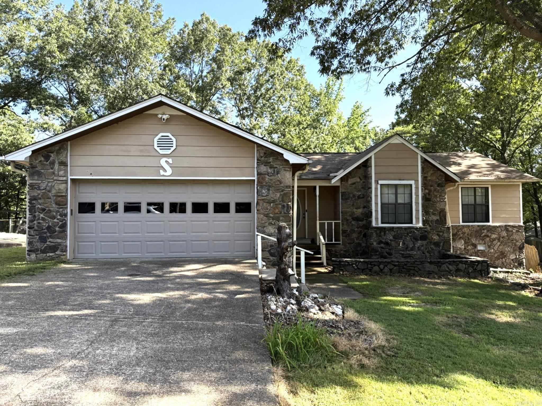 In the heart of Bryant, a great opportunity awaits. With some TLC this home has loads of potential. Walk into a spacious living room with a stone surround fireplace with an electric wood pellet stove vaulted ceilings with french doors open to the covered deck. Convenient pass through closet from the garage to the living room great for your fireplace supplies. Behind the paneling you will find drywall. the Wide hallway leads to 3 bedrooms and 2 baths. The large backyard fenced on 3 sides provides ample space for outdoor activities. Relax on the covered back deck. Sold As IS. Agents See Remarks.