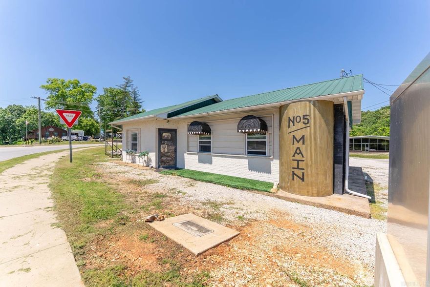 High Traffic Commercial Property on Highway 63 in Mammoth Spring, Arkansas  Located directly on Highway 63 in Mammoth Spring, Arkansas, this high-traffic commercial property offers exceptional visibility in one of North Arkansas’ busiest tourism corridors. Situated across from Mammoth Spring State Park and near the Spring River, the property benefits from constant exposure to both local and tourist traffic, with over 10,000 vehicles passing daily. The 0.5 acre lot features two separate highway entrances for easy access and traffic flow, along with an existing 893 sq ft building already connected to utilities. The property could support a variety of business opportunities including a coffee shop, sandwich shop, drive-thru concept, office, boutique retail space, bait and tackle store, river outfitter, or tourism-focused business. Creek frontage along the north side adds additional appeal for outdoor seating, future expansion, or additional development ideas. Commercial locations with this kind of visibility and proximity to the Spring River and state park are limited in Mammoth Spring.