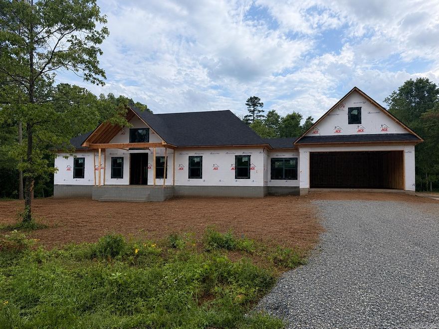 Welcome home to this new construction 4-bedroom, 2.5-bath home situated on approximately 1 acre! This thoughtfully designed home features a spacious split floor plan with a stunning cathedral ceiling in the living room, creating an open and inviting atmosphere. The kitchen offers gorgeous granite countertops and plenty of space for entertaining. Just off the impressive 28-foot-deep garage, you’ll find a convenient mudroom complete with built-in lockers and a bench for added storage and organization. Enjoy relaxing mornings and evenings on the covered front and back porches while taking in the peaceful surroundings. This home combines modern style, comfort, and functionality all in one! Photo has been altered with AI