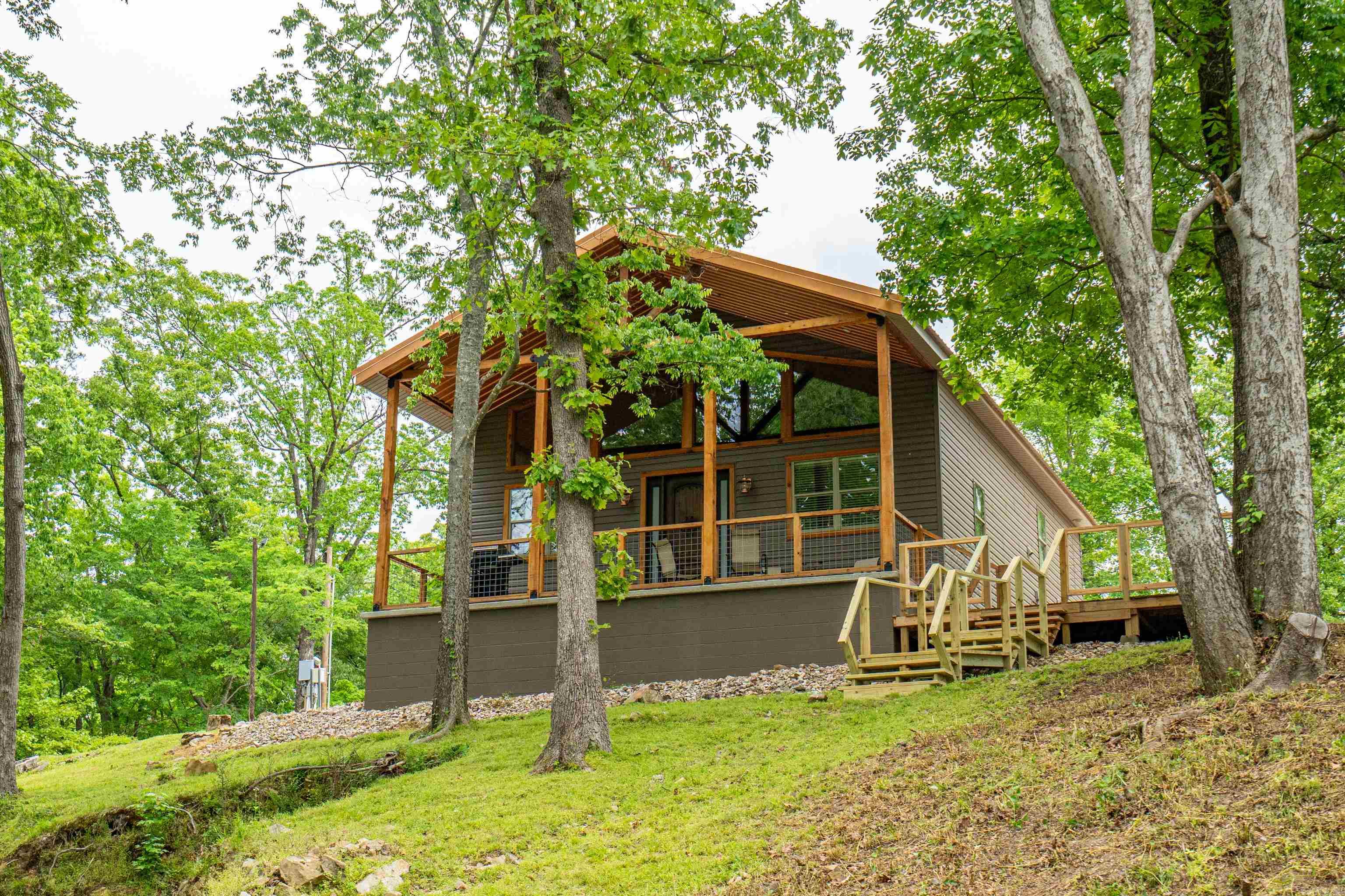 Cabin Life Meets Lake Living at Burchwood Bay! Dreaming of lakefront serenity with a cozy cabin vibe? This is it. Nestled on 1.371 wooded acres in the heart of beautiful Hot Springs, AR, this charming 2 bed, 2 bath cabin delivers the perfect mix of rustic charm and modern comfort. Step inside and you'll immediately feel the easy-breezy magic of open-concept living, tall ceilings, and natural light pouring in from every angle. It’s bright, it’s airy—it’s your escape from the everyday. But the real magic? It’s waiting outside. Step outside and you're greeted by graceful magnolia trees, your own private boat ramp, swim dock, and a spacious outdoor cooking shed with storage- perfect for summer BBQs and weekend hangouts. Property Highlights: - 2 bedrooms, 2 bathrooms on 1.371 wooded acres - 60 feet of lake frontage with 72 feet beside that is common park frontage - Open-concept interior with tall ceilings - Gorgeous magnolias - Private boat ramp + swim dock for easy lake access - Outdoor cooking shed with storage - On-site RV hookup for added convenience or guests