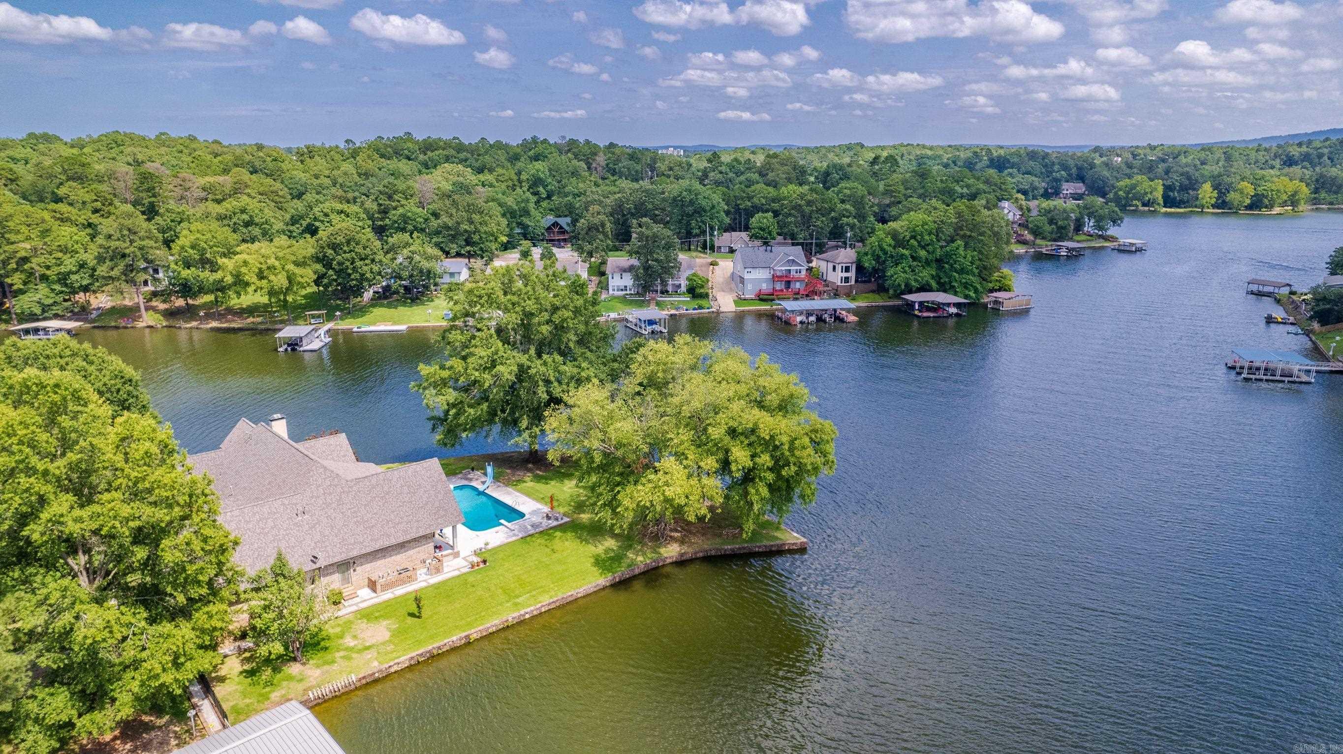 Welcome to this stunning lakefront home nestled on a serene peninsula, offering an unparalleled retreat from the bustling city life. With approximately 762 feet of lake frontage, this property boasts captivating views of the glistening waters. It features a gated entrance, manicured landscaping, swimming pool, a 2 ½ stall covered dock, and an in-ground gas tank for all your fuel needs. As you step inside, you'll be immediately captivated by the open floor plan that seamlessly combines elegance and comfort. The spacious living area is adorned with cathedral ceilings, allowing natural light to flood the space and accentuate the breathtaking lake views. This extraordinary lake home on a peninsula presents a rare opportunity to own a slice of paradise. Immerse yourself in the serenity of lakefront living, enveloped by natural beauty, and create cherished memories that will last a lifetime.