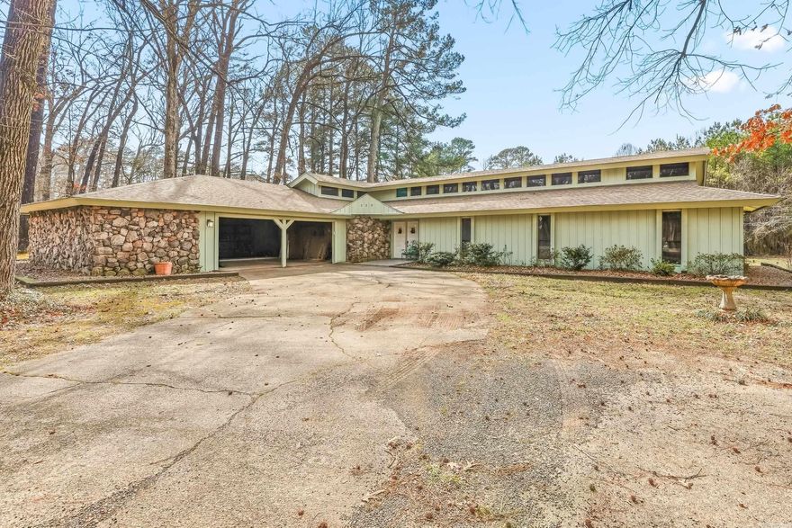 Spacious 4 bed, 2 bath home on 2.86 acres located within the De Queen city limits on the edge of the Joholwood subdivision including .25 of an acre of lot 17 inside Joholwood subdivision for a total of 3.05 acres more or less. With 2,926 sq ft, the home features vaulted ceilings with exposed beams, a dramatic floor-to-ceiling stone fireplace, and large windows that bring in natural light and views of the surrounding trees. The kitchen offers generous cabinet space, updated finishes, and a functional layout for everyday living. Outside, mature trees provide a peaceful setting with a paved driveway and covered back porch off of the master suite. The property sits on the edge of the Joholwood subdivision but is not subject to its restrictive covenants, while still falling under city acreage limitations. A previously identified foundation crack is present; the underlying cause has been removed, see attached foundation report in documents of file.