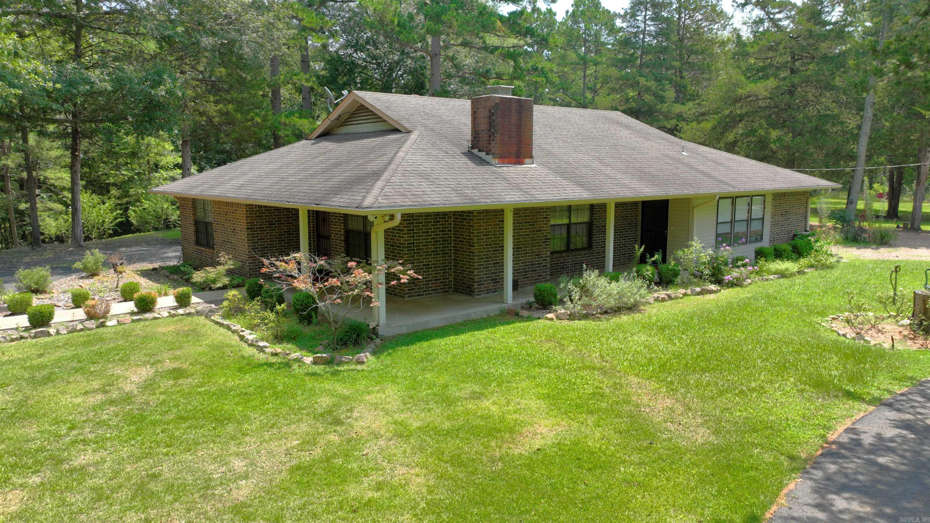 Landscaped by a Master Gardener, enjoy the fruits of experience on this 4.71 acre property while living in the 1,930 square foot three bedroom, two bath brick home surrounded by lush lawns, mature trees, and mountain views. The home features a brick fireplace in the living room, a large eat-in country kitchen with substantial counter space and all appliances included, and a spacious primary bedroom with on-suite bath that contains a sizable double vanity with storage, separate shower and tub, and a linen cabinet. Two additional oversized bedrooms and bath complete that wing of the house. The laundry room has built in cleaning supply storage and another large linen cabinet with washer and dryer included for the Buyer. An office respite is located adjacent to the kitchen, as well as a cozy sunroom. Brand new ROOF! Gas cooking. Wraparound covered porch. Covered patio. Carport. Garage/ shop with wood burning stove for winter warmth. Designated garden plots. Paved driveway. Privacy Fenced and gated. Personal items will be removed, but some furnishings may be purchased by separate agreement.