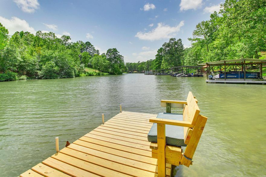WELCOME TO YOUR LAKESIDE DREAM!  This stunning two-story home on Lake Hamilton offers the perfect blend of peaceful living and income producing short-term rental. Upstairs features open floor plan, large stone fireplace, vaulted cedar ceiling, spacious master suite, with en suite bath, modern kitchen, large combination laundry/pantry room, and a wrap around covered outdoor seating area with gorgeous lake views. Downstairs offers private entrance with second living space, second master suite with large en suite bathroom, large guest room, bunk-room, Kitchen/Living combo and guest bathroom making it ideal for guests or continued use as a successful short-term rental.  Enjoy relaxing evenings by the campfire at the water’s edge or unwind in the Jacuzzi tub inside or the hot tub in the screened-in porch. The covered boat slip,  and multiple outdoor seating areas invite you to enjoy lake life to the fullest. Nestled in a quiet, friendly neighborhood within the sought-after Lake Hamilton School District, this property is your perfect personal getaway or income-generating Short Term Rental downstairs!