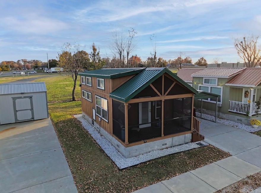 Move-in ready one-owner tiny home in the heart of Rogers! Built by Platinum Cottages, this thoughtfully designed 1-bedroom home with loft blends comfort, style, and simplicity—without the upkeep. Inside, you’ll find an open layout featuring a full kitchen with full-size appliances, a GE stack washer/dryer, generous storage, and a full bath with a walk-in shower. Quality construction includes a permanent concrete block foundation, Hardie Board siding, durable metal roof, and energy-efficient double-pane windows. High ceilings, abundant natural light, LED lighting, and a dual split-system HVAC ensure year-round comfort and efficiency. Additional highlights include an upgraded bidet, upgraded hot water tank, screened-in enclosed porch, and a 10' x 12' storage shed on a stainless steel riser. Located in the well-kept Eagle Homes on Monte Ne community—ideal for those seeking to downsize or embrace a minimalist lifestyle. Enjoy access to a dog park and tornado shelters. Prime location—just a short walk to Veterans Park and minutes from shopping, dining, downtown Rogers, Walmart Headquarters, and Crystal Bridges Museum. Monthly dues of $404 include water, sewer, and lawn care!