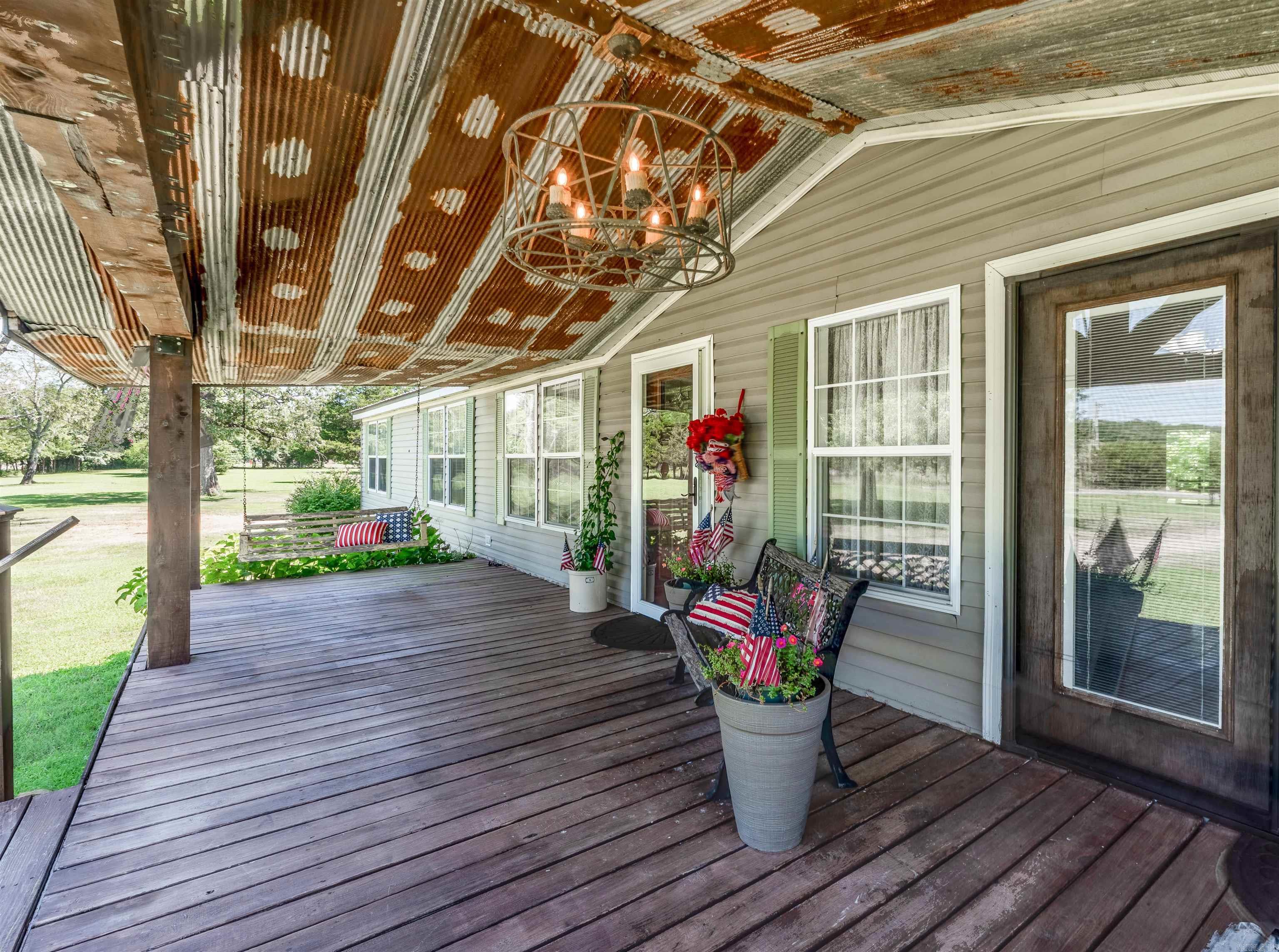 Under Appraisal Value - Beautiful country style home is situated on 5 acres of beautifully landscaped land and 3,000 sq ft of heated and cooled living space. Relax on the huge front porch with porch swings, french doors as you watch the sun set. The home features a metal roof that provides a wonderfully calming sound when it rains, and public water is available for your convenience. For gardening enthusiasts, there is a well and pump on the property too. Large windows throughout the home allow natural sunlight & creating a warm and inviting atmosphere. Inside, is a spacious living room with a cozy wood fireplace, a perfect place to gather with friends and family. The kitchen is a chef's dream, with plenty of counterspace, a custom antique island, and a gas range with 5 burners. A separate pantry provides ample storage for all of your cooking essentials. Outside the living room you will step into the sunroom and be amazed by the stunning views of from the windows. Watch animals and nature in this 300-sq ft sunroom is fully heated and cooled, making it the perfect place to relax and enjoy. Large covered back porch, tiered pad - grilling, firepit, & 30x40 shop.