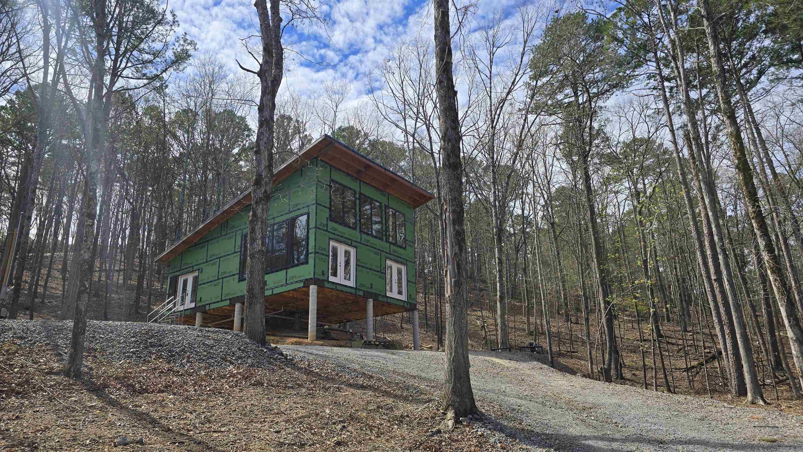DREAM LAKE HOUSE!! This custom beauty is situated across the street from the lake. 360 degree views that are absolutely amazing. Seasonal water views from the huge windows. You can see deer feeding multiple times a day on the natural deer trails. The rock lined wet water creek is beautiful year round. Tons of windows & light! Not a cookie cutter home. Designed by the builder, the monoslope style offers 10 foot ceiling bedrooms & bathroom ceiling and a soaring 22 foot sloped ceiling in the kitchen/living room area. The bathroom has an oversized curb-less shower setup and is plumbed for a 10 foot dual sink vanity. Located only 1 mile from the most popular marina and across the street from the most popular cove on the lake, this home is sure to meet all of your lake lifestyle needs! Get it now while you can pick out colors and finishes. Builder can finish for you, or you can take over the build from here. Water, electrical & sewer is all roughed into the home, ready for outside hookups. Fairfield Bay has many amenities including 100 miles of UTV/SxS trials, boating, hiking/camping, swimming pools, golf and much more for you and your family to enjoy. Www.visitfairfieldbay.com