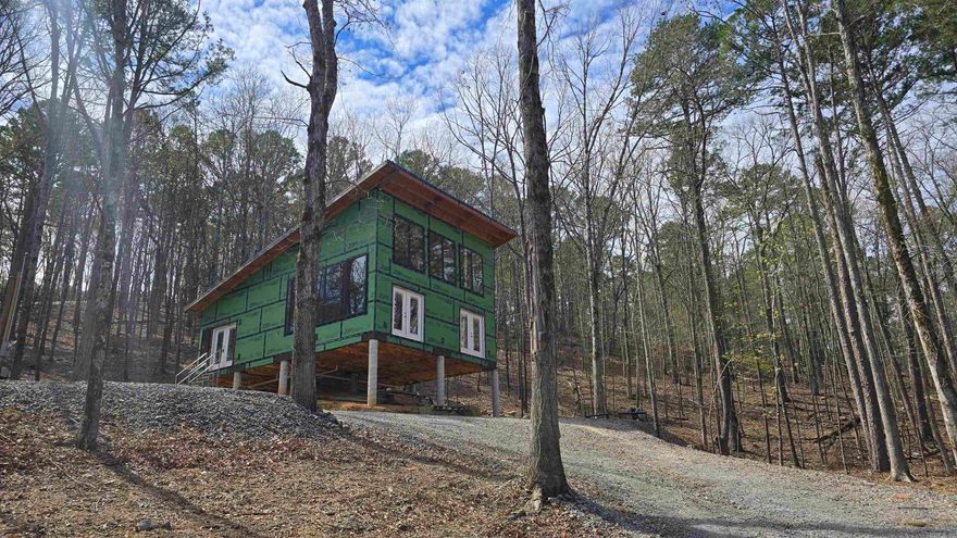 DREAM LAKE HOUSE!! This custom beauty is situated across the street from the lake. 360 degree views that are absolutely amazing. Seasonal water views from the huge windows. You can see deer feeding multiple times a day on the natural deer trails. The rock lined wet water creek is beautiful year round. Tons of windows & light! Not a cookie cutter home. Designed by the builder, the monoslope style offers 10 foot ceiling bedrooms & bathroom ceiling and a soaring 22 foot sloped ceiling in the kitchen/living room area. The bathroom has an oversized curb-less shower setup and is plumbed for a 10 foot dual sink vanity. Located only 1 mile from the most popular marina and across the street from the most popular cove on the lake, this home is sure to meet all of your lake lifestyle needs! Get it now while you can pick out colors and finishes. Builder can finish for you, or you can take over the build from here. Water, electrical & sewer is all roughed into the home, ready for outside hookups. Fairfield Bay has many amenities including 100 miles of UTV/SxS trials, boating, hiking/camping, swimming pools, golf and much more for you and your family to enjoy. Www.visitfairfieldbay.com