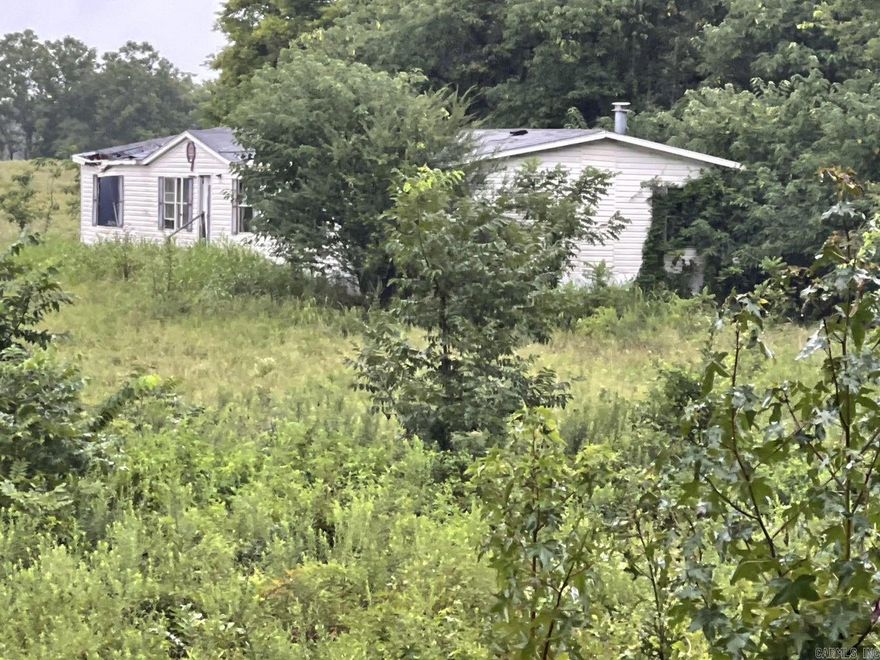 Beautiful secluded 7.22 acres+/- on a paved road that is close to town with no restrictions! Land has a small creek that runs thru it and has utilities previously set up, might need some work to get started again. Property has a 2000 trailer with title that needs lots of work and has been given no value. There is rural water and a well but do not know the condition of the well or the septic system. There is also an old storm shelter. This property is ready for you to build or have a mini farm.