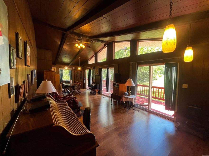 Your own piece of the Ozarks awaits you at the end of Mockingbird Lane!  Enjoy the peace this Mid-Century Modern home brings at the end of the street, giving you the privacy you seek. The wrap around deck will invite you in, and gives multiple sitting areas around the home for entertaining, or just enjoying your morning coffee alone. Beautiful windows adorn the living area, with a vaulted ceiling, rock fireplace, 2 bedrooms,1 bath, CH/A, concrete driveway and carport.   At the rear of the carport is a tool/workshop storage room, and also includes a separate storage building in the back yard!  NOTE: Blue metal carport not included in the sale.