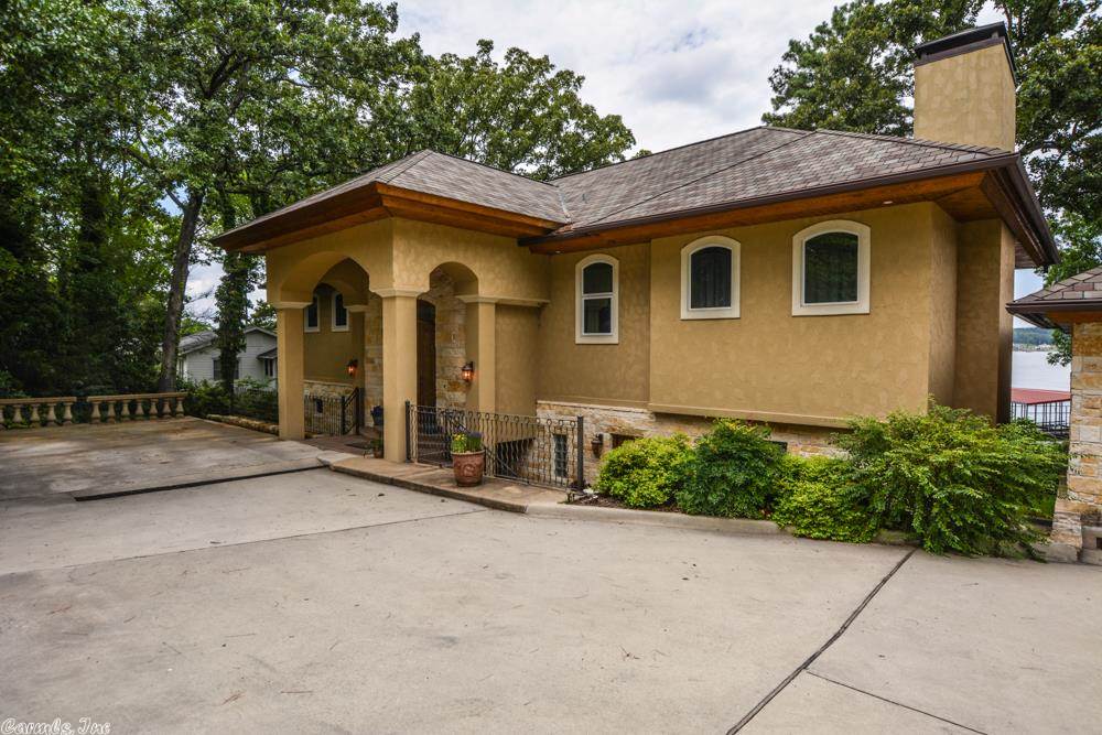 This home is a newly built architectural marvel with an Austin chalk stone and stucco facade built on a small hillside offering spectacular main channel views across the beautiful Lake Hamilton. Its sumptuous interior spans 4,318 square feet on two levels with easy entry to both levels from the front. The home has an irresistible personality--it is a series of grand-sized rooms connected with ribbon walls of glass that effortlessly lengthen the view straight through to the sprawling outdoor living spaces.