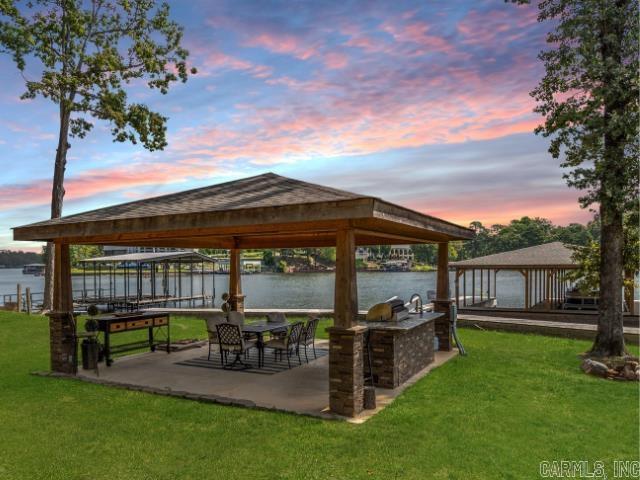 Embrace lakeside living with 100 feet of stunning Lake Hamilton frontage and a new, 2-stall covered stationary boat dockāperfect for endless days on the water. The fabulous outdoor kitchen sets the stage for unforgettable lakeside gatherings. Step inside to find a spacious and inviting layout with 4 bedrooms, each featuring stunning lake views, 2.5 baths, and a versatile bonus/bunk room that could easily transform into a game room. Need extra space? The detached garage has been converted into a private guest suiteāaccommodating up to six guests with a full bath, making it an ideal retreat or additional rental opportunity. Currently operating as a successful short-term rental and offered fully furnished, this property is ready to generate income while serving as your dream lake getaway. Itās a win-win, providing the best of both worlds! Looking for more? The adjacent lot with 98 feet of lake frontage and an existing boat dock is also available for purchaseāoffering even more possibilities!