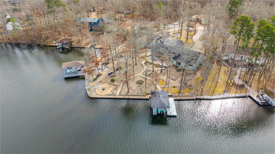 Exquisite lake views define this updated one-story contemporary home on a most scenic point lot on Lake Coronado, Hot Springs Village’s 2nd largest lake. Rare offering with over 140’ of lake frontage, exceptional privacy, and easy walk-out access to the water. Curb appeal includes native trees, Quartz boulders, rock landscaping, and sidewalks surrounding the home. A lake-fed sprinkler system with new pump services the main beds. Enjoy the boat dock with lift—ideal for a 20’ pontoon with 90HP Yamaha that conveys—plus a permitted lakeside fire pit. Designer Typhoon Green granite highlights the kitchen, coffee bar, baths, and laundry, centered by a large island with Italian ZLINE gas cooktop. Mohawk “Wheatfield Oak” laminate flooring runs throughout for durable, scratch-resistant, no-carpet lake living.The primary suite offers patio access, dual vanities, dual closets, and ensuite. This 3BR/3.5BA home also includes a private study, Arkansas room with built-in bench, oversized laundry/craft room with king Murphy bed, ample patio space, and oversized garage. Energy-efficient features include lake-sourced geothermal HVAC, new Trane bedroom wing system, hot-tub-ready patio, and 2017 roof.