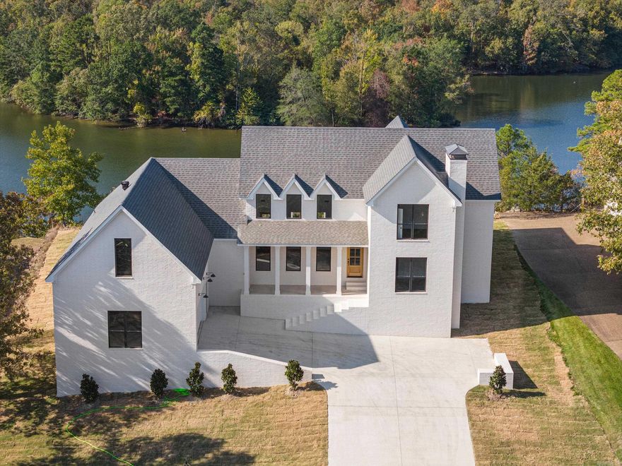 This L-shaped, 2-story, modern Farmhouse w/ views of Lake Hamilton is highlighted on the exterior by dual fireplaces, metal roofs, front & back porches w/ board & batten siding. Inside immediate impressions are made by a soaring 2-story-high, wood-beamed cathedral ceiling in the great room. A trio of tall windows complement both the front & rear walls of the great room offering views through the front porch & rear patio. Kitchen w/ expansive work island, lies beneath its own beamed ceiling & is open to the dining area. The main floor’s primary suite features his & her walk-in closets, his & her vanities in the bath. Primary suite can be entered through an alcove off the great room or from the laundry area. Second suite on the main floor lies behind the kitchen, features a walk in closet & private 3/4 bath. Upstairs, bedroom 2, 3 & 4 share a hall bath. Bedroom 4 has tall cathedral ceilings. Back on the main level, the 2-car garage includes space for a workshop. It accesses the home through a mudroom with bench, lockers & a coat closet. Owners can enjoy a landscaped gated entrance along with access to the boat ramp. Est completion 8/24. *Zoned for 2 stall boat house & swim platform!