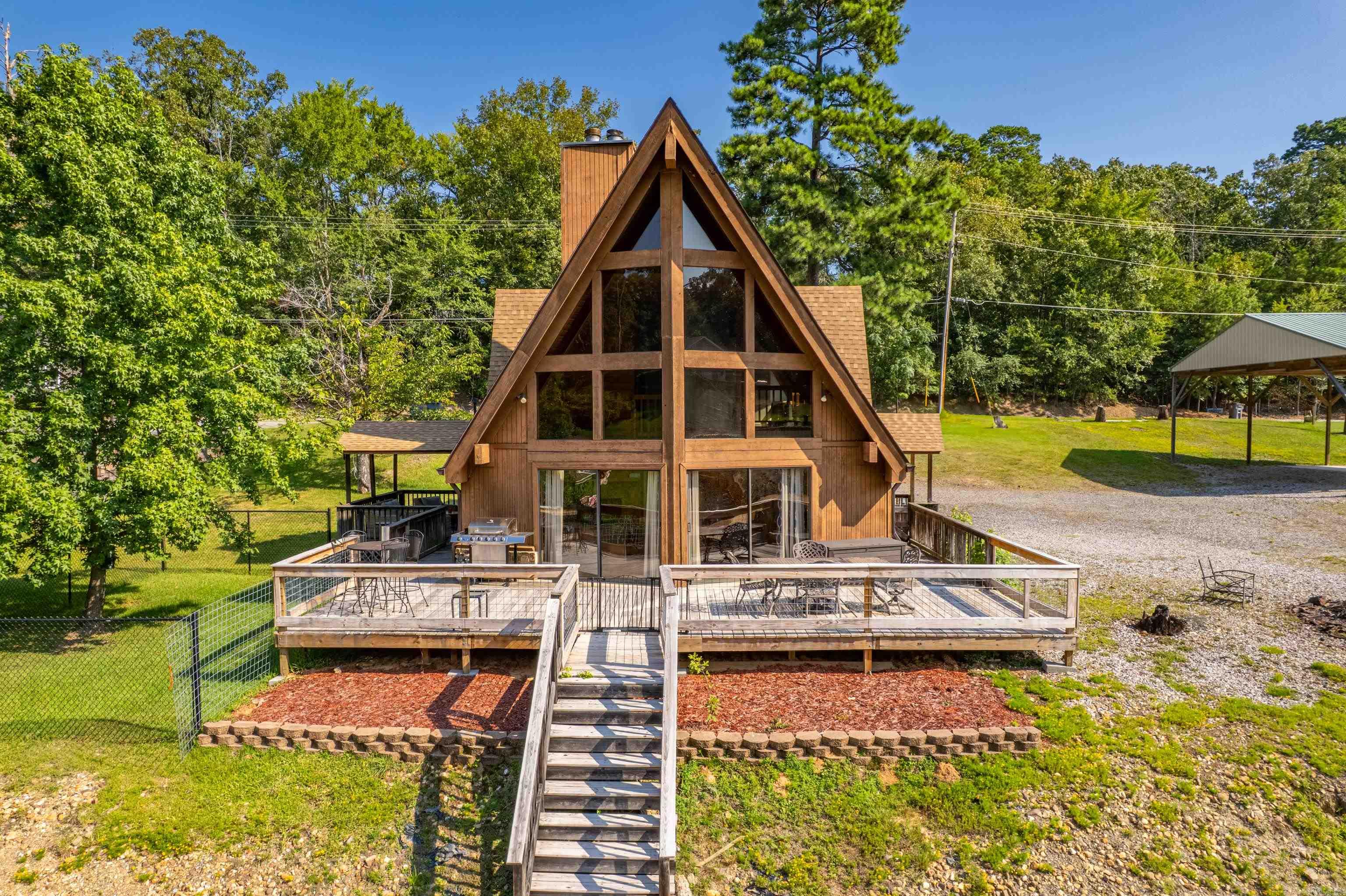Discover your perfect lakefront escape with this charming 3-bedroom, 2-bath A-frame, fully furnished, home on Lake Hamilton. Tucked away in a peaceful cove, walking distance to Sam’s Pizza, and the best of Hot Springs, this fully furnished home is ready for year-round enjoyment or weekend getaways. The home’s cozy, classic layout offers defined living spaces and exceptional comfort. The spacious living area is bathed in natural light, thanks to floor-to-ceiling sliding glass windows that frame stunning lake views and let the outdoors in. Step right out onto the back patio, the perfect spot for morning coffee or sunset dinners while overlooking the water. Enjoy outdoor living at its best with a swimming dock, boat dock with a lift, a pole barn with a concrete slab—ideal for storage, entertaining, or even future workshop space. A dedicated RV hookup adds even more flexibility for guests or travel lovers. Small storage building to store mowers, blowers and such. This well-maintained home combines classic lake house charm with unbeatable location and amenities—schedule your showing today and start living the lake life you’ve always dreamed of! **STR's are available with the sell**