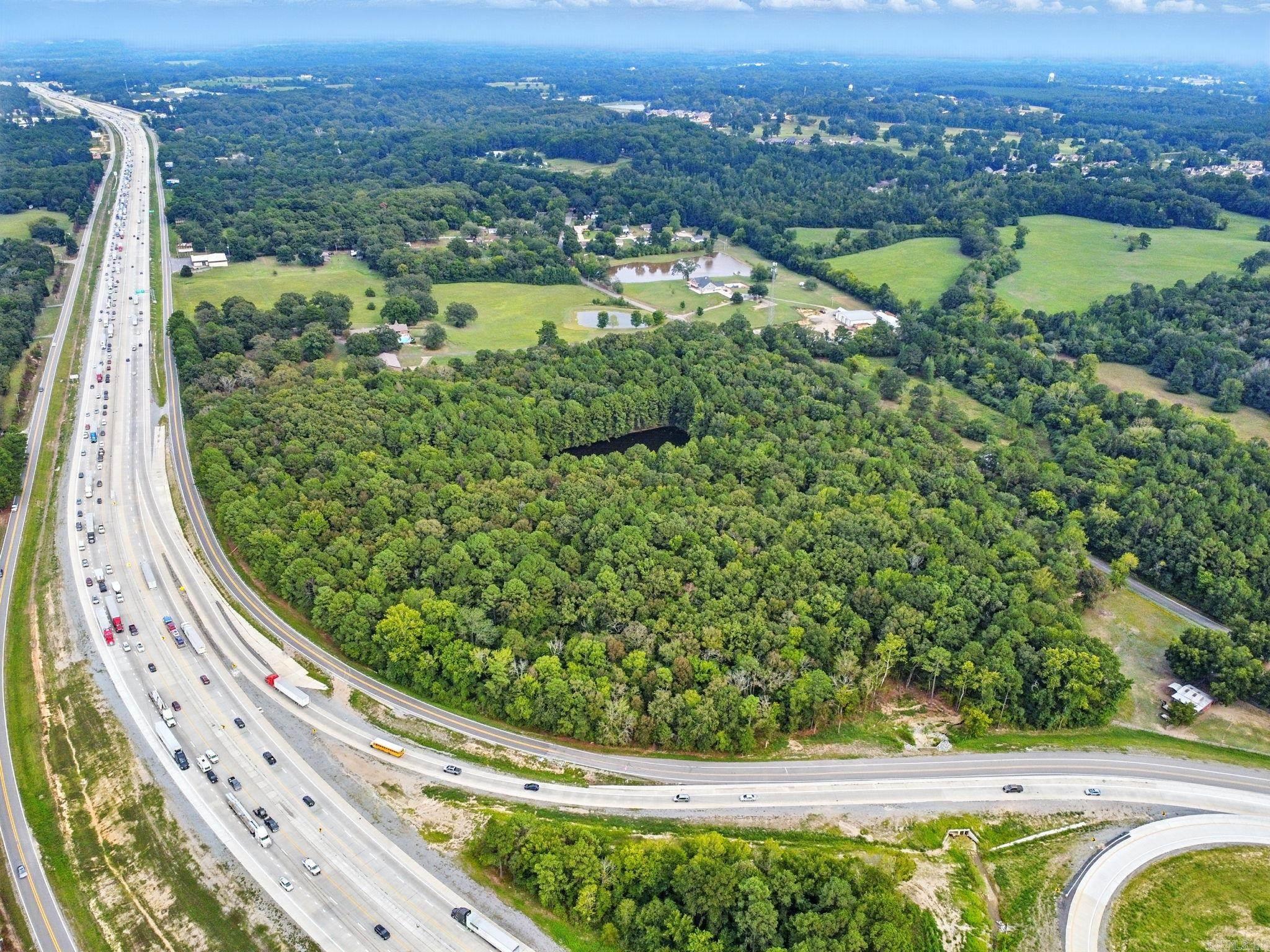 Approximately 24 acres with a pond located on the I-30 South frontage road, this property is ready for your development whether it is commercial or residential. Located in the county, this property has not restrictions and offers limitless possibilities. The area contains both residential properties as well as businesses and manufacturing companies. Located near the developments at the Highway 67 area where new schools, Buckee's and other construction is in progress, this is a prime location for your new or existing business to expand. Call your agent or me to set up a private showing.