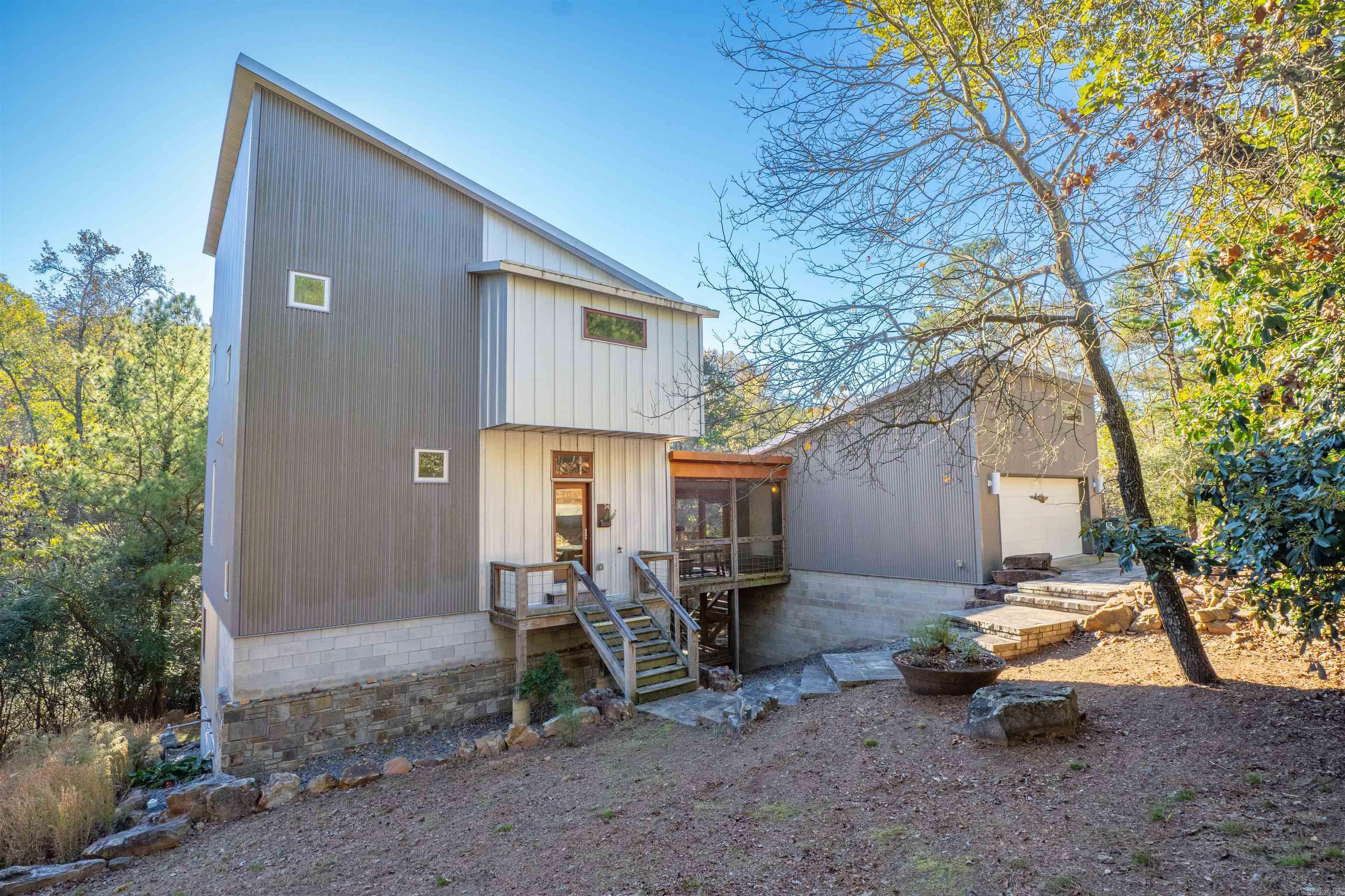 Exceptional contemporary home in highly sought-after Woodglen! This one-of-a-kind property is set on a private, wooded .84-acre lot backing to Jimerson Creek, offering a rare blend of modern design and natural serenity. Inside, you'll find a warm yet sophisticated living space featuring walnut floors, abundant natural light, and picturesque views through expansive windows. The screened porch overlooks a peaceful stone patio with fire pit, perfect for outdoor relaxation and entertaining. Upstairs, the primary suite offers a private retreat with its own balcony, a spacious spa-like bathroom, and a generous walk-in closet. Downstairs includes a large flex bedroom with potential to be partitioned into an additional bedroom or office. This versatile space features two garage-style doors that open to a second screened porch, seamlessly blending indoor and outdoor living. Agents: see remarks for additional details.