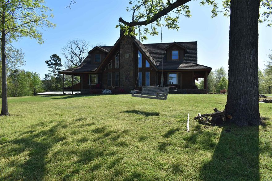 The mountain views in nearly every direction from the wrap around porch of this two-story home are nothing short of awe inspiring! This 4900 square foot log siding home is perched atop a small knoll near the back of the 15 +/- acres that surround it. The home not only boasts an amount of square footage that is hard to find, but a combination of rustic finishes and beautiful craftsmanship. As you walk up the stone walkway to the front of the home, you will notice the beautiful masonry around the wrap around porches, the perfect place to enjoy a cup of coffee as you watch the sunrise over the Ouachita Mountains. The main level of the home has a large living room with a vaulted ceiling and fireplace, and windows with views of the mountains. The spaciously designed floorplan has two bedrooms and two full baths on the main level of the home, accompanied by a large laundry room just off of the two-car carport. Upstairs, two suite style bedrooms are connected by a loft overlooking the living room. The full basement downstairs is the perfect quite space for a home gym, office, or separate living quarters. There is a half bath, as well as a walkout door to the rear of the home.