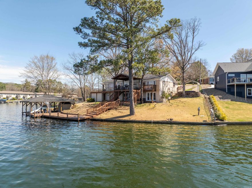 Discover unparalleled lakeside living in this stunning four-bedroom, four-bathroom brick home, perfectly positioned on the coveted mainchannel of Lake Hamilton. With approximately 150 feet of prime shoreline, this property offers panoramic, year-round views of the openwater—arguably one of the best vistas on the lake. Whether you're sipping your morning coffee or toasting the sunset, the scenery fromthis home never disappoints. Situated just minutes by boat from Bubba Brew’s Restaurant and Pub, this property offers bothconvenience and entertainment right at your fingertips. Easy water access to dining, live music, and lake-life fun makes this home astandout for both weekenders and full-time residents alike. Step outside to your private lake oasis, where a covered boat dock with jet-skislip awaits just steps from the back door. The dock also features a built-in waterslide, making it a hit with kids. And after a day on thewater, unwind on the covered main-level porch, complete with a gorgeous custom wood ceiling and plenty of space to entertain. Inside,this spacious and airy home is thoughtfully designed with an open-concept layout perfect for both entertaining and everyday comfort.