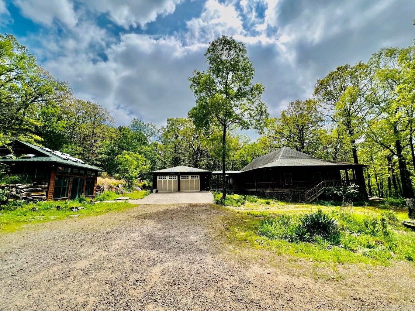 Over 2000 sq ft of Custom built home never before on the market just 2 miles north of Clarksville city limits 77.7 acres of wooded privacy. This custom built home has hardwood floors, oak built-ins everywhere. 3 bedroom with a 4th bonus room with two walls of windows all top-of-the-line wood framed. Open concept with a master chef's kitchen, gas stove, 2 built-in sinks, overlooking your massive 1000 sq ft of deck and woods for that large party. Beautiful built redwood cedar home with covered porches on all sides, a detached 34 x 24 garage with shop plumbed for a bath. A 40 x 30 cedar shop has 2x6 insulated walls plumbing for its own bath. Also a custom built greenhouse with floor to ceiling cabinetry & lots of landscaping with large native rocks meandering pathways through the flowers