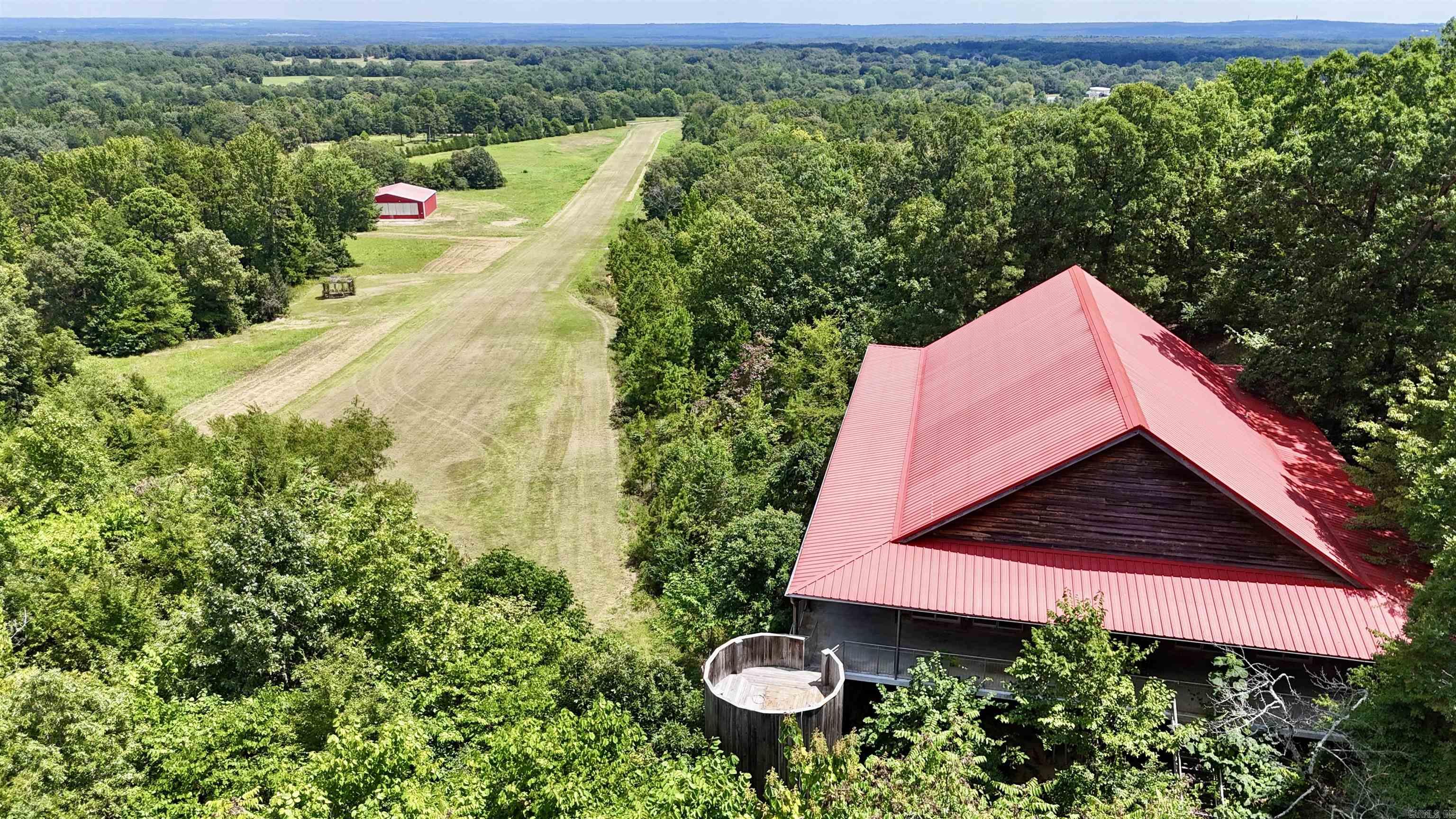 Beautiful, custom built home on elevated slab with 33.33 acres, mountain views, private airstrip, hangar/shop, 4,000 sq ft, 3 beds, 3.5 ba, in-law quarters/4th bedroom/bonus area. Grand details: picturesque views from every angle, all windows are glass sliding doors, extra wide door frames, Double sided stone fireplace, grand great room with gorgeous views, authentic tin tile ceilings throughout, vaulted/tall ceilings, spacious bedrooms, wood flooring, granite countertops, ss appliances, custom cabinets, 3700 sq ft of wrap around porches, custom made steel 12-foot water wheel, stocked pond, 2000 x 60 ft runway (FAA identifier 35 AR Sweet Springs Airport) located on property. Hangar/shop is 3,600 sq foot with half bath. The engineered structure is constructed from fabricated steel including floor, porch, walls, and roof. Outside is covered in 1 inch cypress siding. The runway and Hangar can be converted into anything you desire. Perfect private residence or could be a Venue/business of your choosing. Request a copy of the Seller info sheet & Video/drone tour. Do not miss this "Once in a Lifetime Opportunity" to own this unique property.