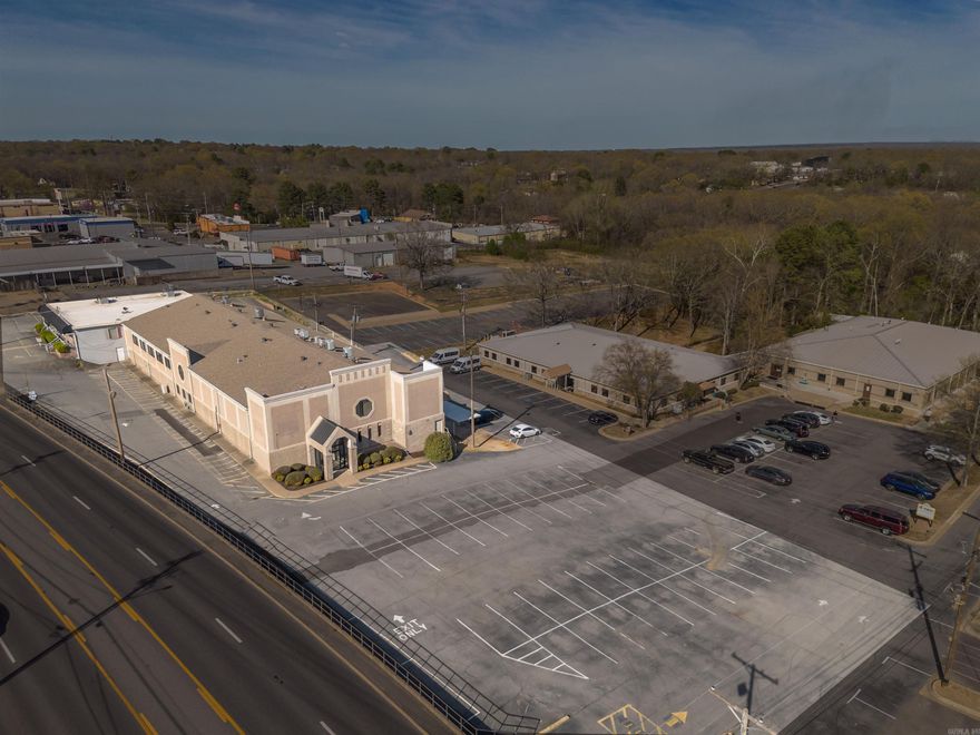 Prime commercial opportunity in the heart of Sherwood! This expansive 1.77-acre property is ideally located on Highway 107, directly across from Arvest Bank, offering incredible visibility and traffic exposure. Boasting 17,960 square feet, this full-service office building includes two stories of flexible space suitable for a variety of business needs. 2nd building included in the purchase totaling 22,000 sqft.  Originally built in 1980, the property features additional improvements such as asphalt and concrete paving, metal fencing, and several canopy structures. Zoned for general office use and situated within minimal flood risk (Zone X), this well-positioned parcel lies within close proximity to schools, neighborhoods, and other high-traffic commercial destinations. Whether you're looking to expand your current business, develop an investment portfolio, or establish a new headquarters, this property offers both scale and strategic location. Don't miss your chance to own a key piece of Sherwood's commercial landscape!