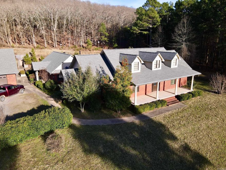 This exceptional 15.32-acre property just outside Russellville, Arkansas offers privacy, acreage, and convenience less than one mile from I-40 on the west side of Crow Mountain with views of Mount Nebo.  Built in 2005, the custom 3-bedroom, 2-bath brick home features 3,106 square feet with a split floor plan, formal and casual living areas, and a spacious family room with wood-burning stove. A separate formal living room and a glass-enclosed sunroom overlooking the landscaped, park-like backyard provide excellent entertaining space and year-round enjoyment.  The kitchen includes custom oak cabinetry with glass fronts, abundant counter space, an eat-in area, and a central island. The oversized primary suite offers large walk-in closets and a private bath.  Improvements include two detached brick garages: a 1,600± sq ft garage with two overhead doors, finished interior, office, and built-in safe room, plus a 1,333± sq ft 220-wired workshop. A hillside storm shelter with electricity adds security. Gated entry, brick columns, fencing, mature timber, small vineyard, and chain-link fenced backyard complete this private yet conveniently located estate.