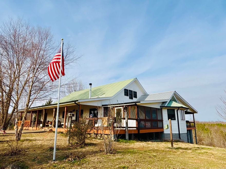 This scenic vista is located in one of the most coveted areas of the Ozarks with a custom-designed farmhouse perfectly placed to capture panoramic mountain and valley views of the surrounding 165 acres+/- offering lush, wooded sections for wildlife and marketable timber, plus pasture for livestock. The beautiful farmhouse has an open concept with the timeless warmth of wood walls & ceilings and large windows for natural light and views. There is well-appointed outdoor living spaces designed for enjoying quiet mornings or evening sunsets including a screened-in porch, sunroom, wrap-around front porch with swings, plus a covered side deck. The magazine worthy design and interior features almost 3600 sq ft, oversized kitchen island, built-ins for storage, walk-in closets, a large family room, 3 wood burning stoves, and upstairs bonus area perfect for a den, bedrooms, game room, or home office. Outside has a concrete sidewalk, storm cellar, RV Carport, detached 26X24 garage, 2x40 shop w/lean-to, 12X14 utility building, chicken coop, & other outbuildings. Far too many features to name! Many of the unique antiques, furnishings, furniture, and decor may be negotiable.