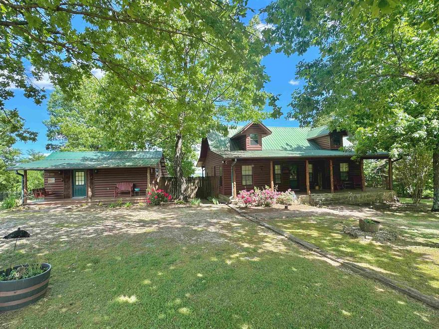 Nestled in the Ozark Mountains, sits this well maintained FULLY FURNISHED Cabin & guest house with an amazing view!! The main cabin features an open living area with tall wood ceiling along with a wood burning stove and a spacious kitchen adjoined by a walk in pantry/laundry room. The master bedroom is also on the main floor with a completely remodeled bathroom. Upstairs is a 1/2 bathroom, open bedroom, and a sitting area/nook. Off the back deck of this home is a large patio area made of stone, built in firepit, and plenty of room for outdoor entertainment. The property also takes in a portion of a shared pond! The guest cabin features 1 bedroom/1 bathroom and makes the perfect guest cabin or vacation rental! The main home has had my updates recently! An added BONUS is an additional lot with a storage building, carport covering, and orchard! This property is beautifully landscaped and very inviting. Located a short drive to Downtown Mountain View!