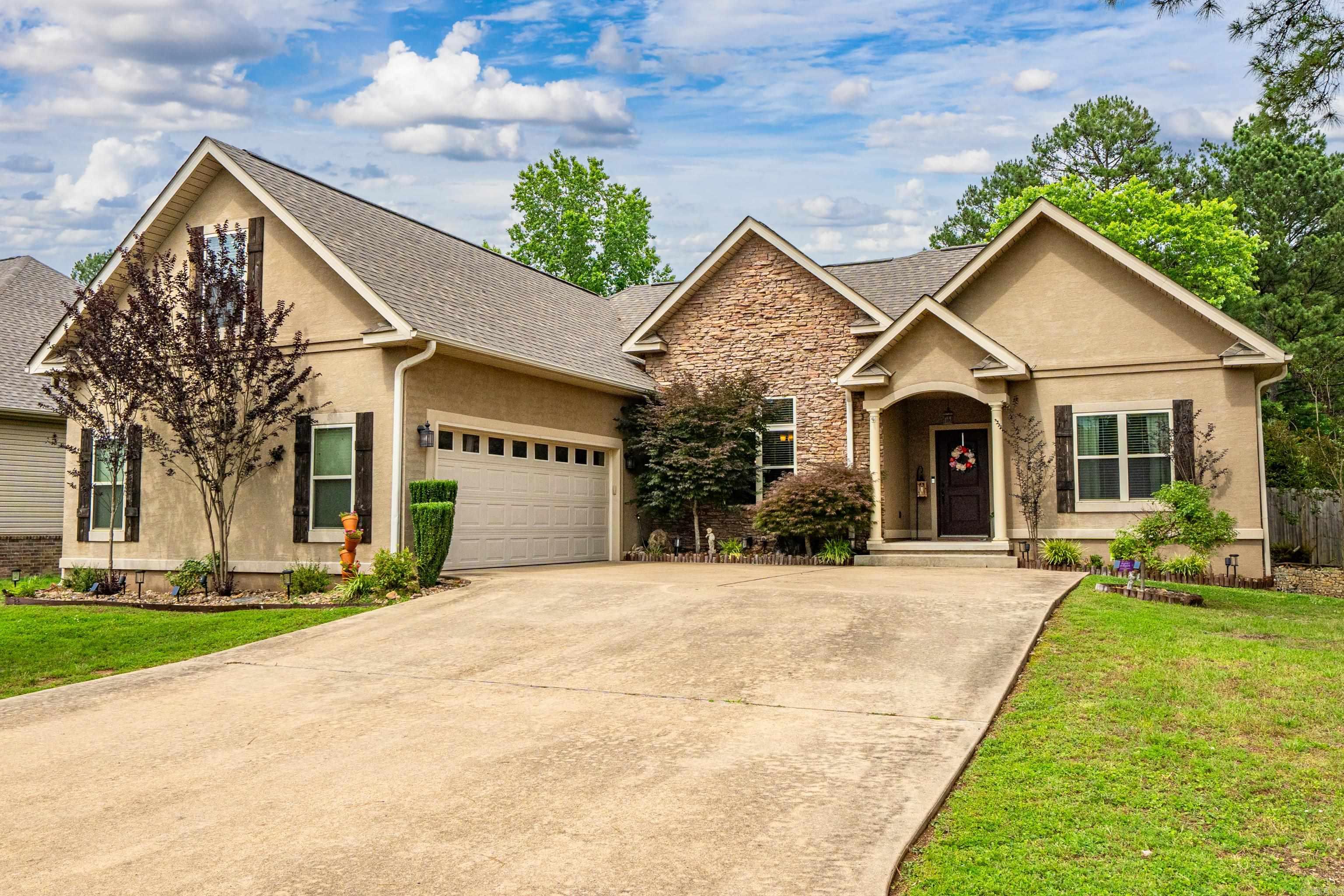 Introducing 282 River Mill — a charming 4-bedroom, 3-bath stone and stucco home tucked in a quiet cul-de-sac in a peaceful neighborhood. Built in 2011, this 2,257 sqft home blends comfort and style with tray ceilings, granite countertops, and a spacious kitchen featuring stainless steel appliances, built-in lazy Susans, and a pantry. The master suite offers a walk-in closet and Jacuzzi tub, while the upstairs bedroom with its own full bath and walk-in closet is ideal for guests, teens, or a private office. Enjoy a fully fenced yard with an additional lot behind the home, plus recent updates like new shutters, soffits, window screens, and a newer roof. Cozy up by the wood-burning fireplace in cooler months and take in beautiful lake views year-round. Located in the Lake Hamilton School District with an EV charging port in the garage and just 10.9 miles from Lake Ouachita — this home has it all.