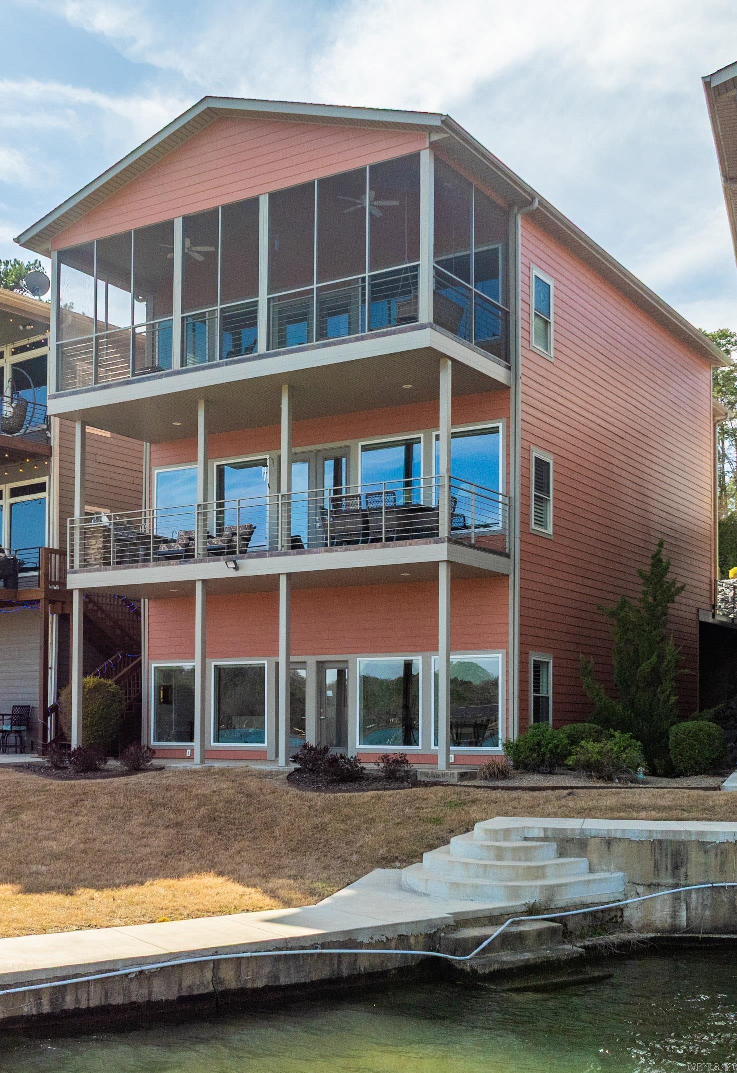 Luxurious Waterfront Living and Investment Opportunity. Presenting an exquisite three-level modern waterfront townhouse boasting 4,050 square feet of sophisticated living in the esteemed Hamilton Peak community. This exclusive enclave comprises only 4 townhomes,ensuring unparalleled privacy and stunning panoramic views of Lake Hamilton. What makes this property truly exceptional is the HomeOwners Association (HOA) allowance for short-term rentals, making it a savvy investment choice for Airbnb. Top-Level Luxury ascending the stairs,you'll find a versatile bonus room leading to three bedrooms, two baths, and a convenient laundry room. The grand primary suite positioned lakeside, featuring vaulted ceilings and expansive glass walls that offer an uninterrupted connection to the serene lake. Step onto the screened balcony to immerse yourself in the breathtaking views. The luxurious primary bath has a double sink vanity, a spacious walk-in shower, and an indulgent soaking tub. Main Level Elegance. The main level seamlessly merges an open concept floor plan, encompassing the kitchen, family room, and dining area. Every seat offers panoramic lake views. Only $205 per sq ft. Great price!!