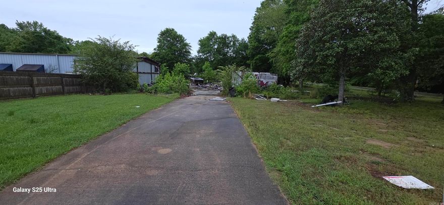 Corner lot with mature hardwoods. Prior structure was a shop with apartment that burned. Current owner is trying to get the debris cleared, however property be sold as is. Remaining side if the building is occupied and owned by a different party. Good investment potential, subdivisions being developed directly across the street.
