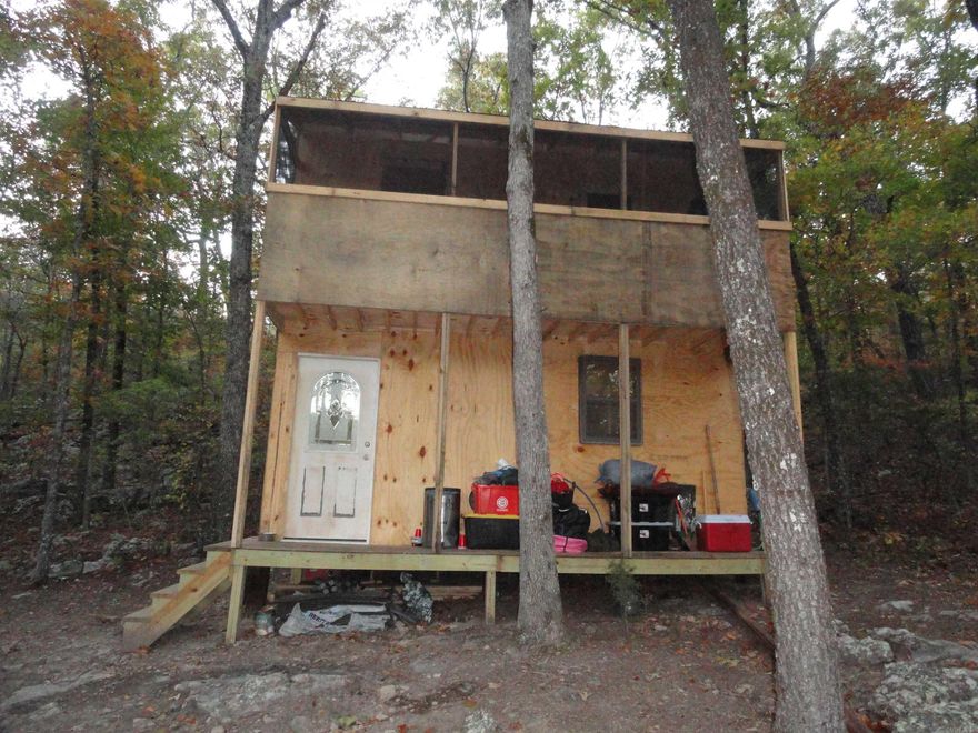 Off grid, solar powered, unfinished cabin on 10 acres in the Ozark Mountains of North Central Arkansas. This property has a 2-story cabin, roughed in and in the dry. Finish it to your liking. Spring water is available near the cabin and could be developed to provide water to cabin. The solar panels and battery bank is new and operational, and the cabin is partially wired with lights, outlets and a regular sized refrigerator. There is also a regular sized propane cook stove for your cooking convenience.  At the present time, there is an outdoor, on-demand, propane water heater for outdoor showering. The upstairs has screened-in covered porch. The property is filled with trees except for what has been cleared for the cabin area. The property also has a seasonal creek that should hold pockets of water even in the dry part of the season. Use the property for a deer hunting camp or live full time off grid. No septic system is in place at this time.