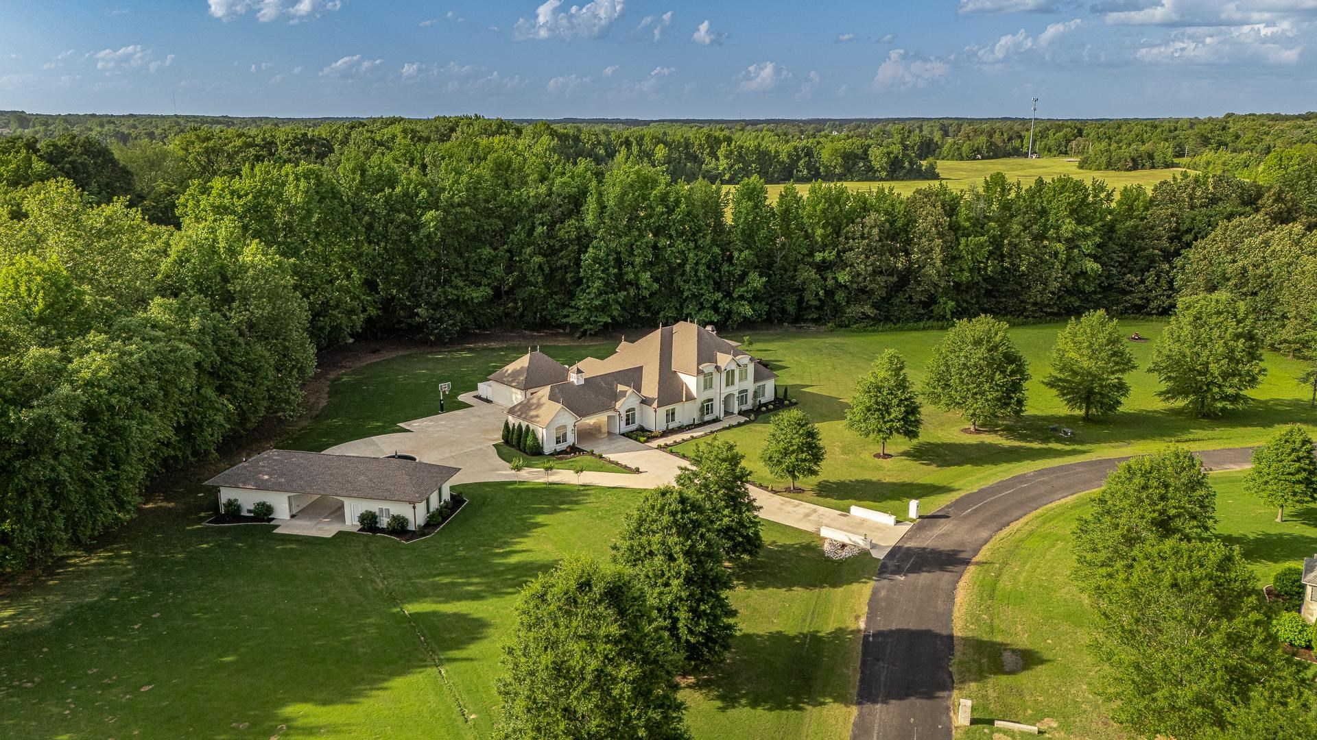 This stunning estate blends luxury, comfort, and elevated design into one unforgettable address. The main-level Owners’ Retreat is a true sanctuary with marble floors, a spa-like steam shower, slipper soaking tub, double vanities, private water closet, and two custom closets—one a built-in safe room. A separate main-floor guest suite adds comfort and privacy. At the heart of the home, the chef’s kitchen stuns with a grand island, premium finishes, and seamless flow to the great room, office nook, wet bar, and guest half bath. The laundry room even includes its own exterior door for added convenience. Upstairs offers three additional bedrooms, two full baths, a second office nook, and abundant storage. Outside is where this home truly shines—relax by the sparkling pool, rinse off in the outdoor shower, and cook in a fully-equipped outdoor kitchen with built-in grill, prep space, and bar seating. The detached pool house brings year-round entertaining to life with a wood-burning fireplace, full bath, and wet bar, while a separate studio apartment with kitchenette and full bath offers space for guests or creative escape. With five garage bays and flawless attention to detail throughout