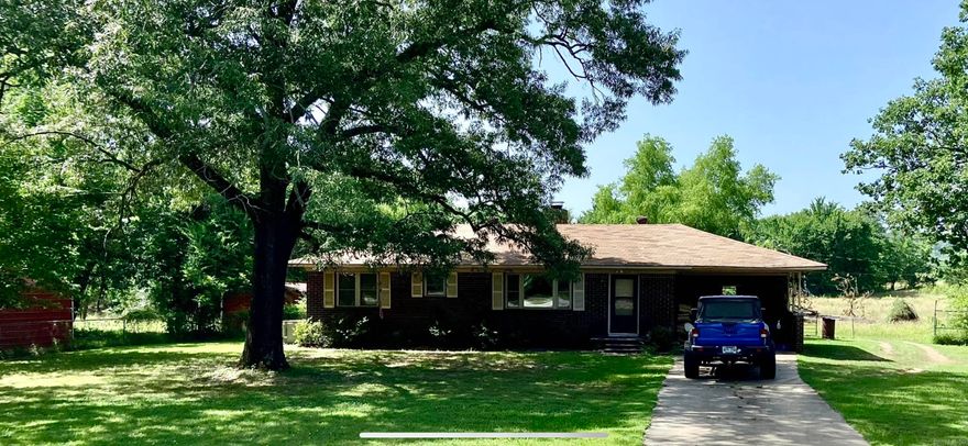 Farmette near Greenwood on a paved road! Ranch style Brick home with 3 bedrooms and 1 bath is powered by SOLAR panels with batteries and  2 generators as well,  Electric bill is almost non-existent. 2.83 acres with fencing and cross-fencing with wire cattle height panels for your animals to graze and roam.  There are stalls for goats, sheep, calves, or you can expand for horses in the barn next to the shop.  The home had a new roof installed in 2019 and has a carport attached that could be turned into a bonus room since there is parking in the garage out back.  Under the carpets there are wood floors if you want to uncover them.  A Large wood-burning fireplace with blower heats the whole house!  Close to shopping and Fort Smith but still with a country feel.  Mountains can be seen from the back pasture.  The property could be divided and another house put in back.  A few updates are needed to personalize it and to make it your own! Central heat is not working but Air is working.