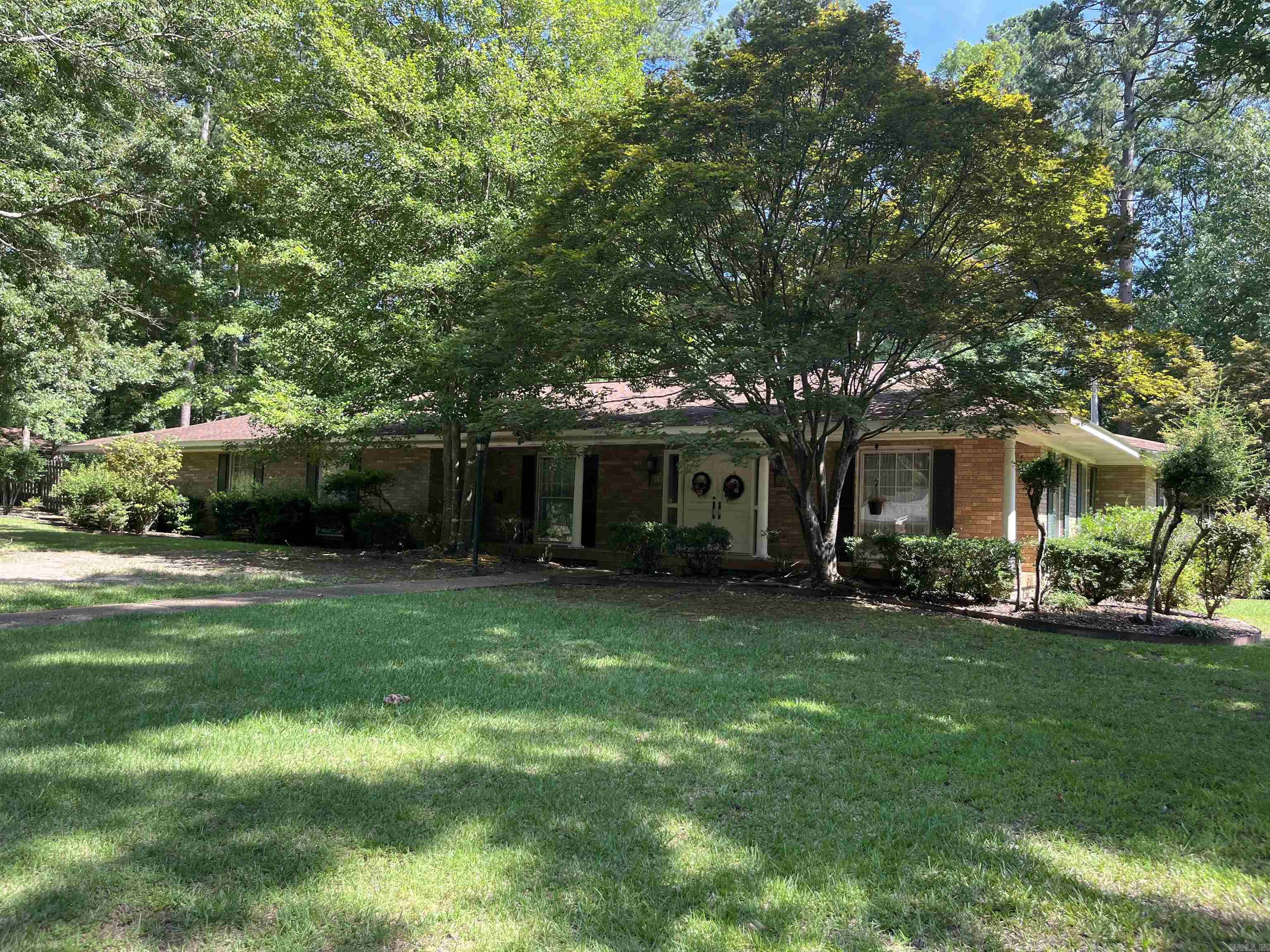 This home welcomes you to a lush front yard and exquisite curb appeal. Located in the heart of Magnolia and just minutes from Southern Arkansas University. To the left of the entry is a formal living room and to the right a formal dining room anchored by an elegant chandelier. Designed and built for entertaining the home features a massive den with fireplace that provides a vocal point. Both stylish and practical, the kitchen is equipped with undercabinet lighting, abundance of cabinets, refrigerator, double oven, cooktop, trash compactor, and dishwasher. The laundry room with sink is adjacent to the kitchen. Don't miss the beautiful office with wood cabinets and fireplace that adds even more character and charm. The spacious master bedroom has an ensuite bath with double sinks, shower and walk-in tub. There are two additional bedrooms, hall bath and half bath in hallway for guests. When driving into the carport you are welcomed with a black wrought iron gate leading to the patio. Other amenities include additional parking, sprinkler system, guest house with kitchen and bath, and fully fenced yard. For your private showing give Linda Anders at Jan's Realty a call 870-904-0147.