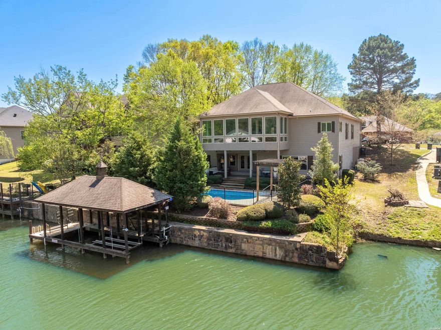 Experience luxury lakefront living in this exceptional 5-bedroom, 3-bath home located in Lakeside School District. Perfectly positioned along on the shores of Lake Hamilton, this stunning residence combines elegant design with practical comfort, ideal for full-time living or a weekend getaway. The spacious, light-filled layout features an inviting living area anchored by a cozy fireplace. The gourmet kitchen boasts granite countertops, a custom tile backsplash and dual ovens - all open to the living & dining spaces. Four bedrooms on the main level with a very large primary suite. The lower level features an additional bedroom and bathroom, along with a large family room - perfect for guests, game day gatherings, or multi-generational living. Outside, enjoy the ultimate backyard oasis with a sparkling pool and plenty of space to entertain. The dockside patio and single-stall covered boat slip provide direct lake access, so you can load up the family and hit the lake in seconds. With upscale finishes, generous living space, and prime location, this lakefront gem has it all.