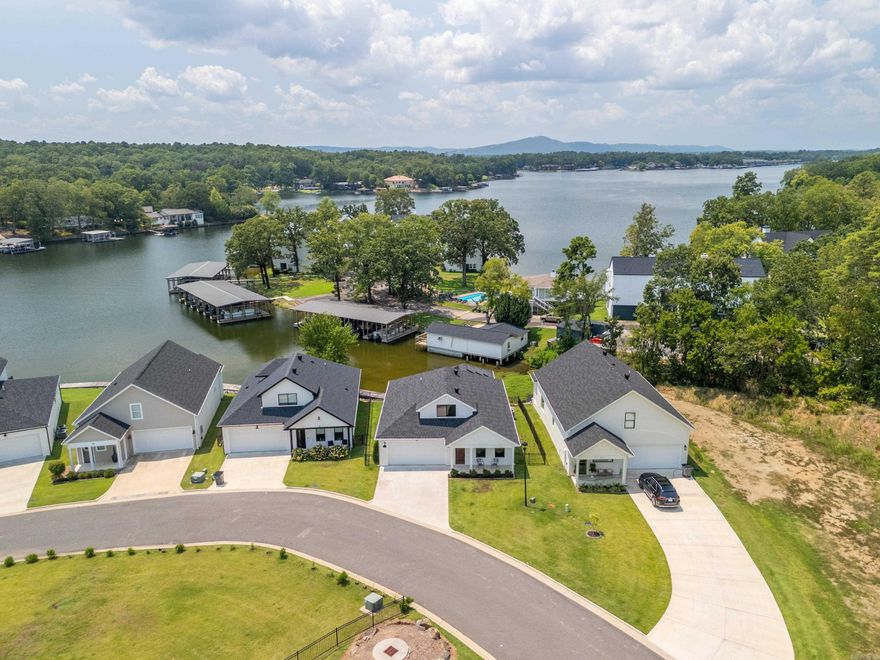 Enjoy lakefront living in this beautiful 2022 built home tucked in a quiet cove on Lake Hamilton. Enjoy effortless main-level living with a no step entry and open, light filled floor plan. Designer details shine throughout--from elegant lighting and custom drapes to premium LVP flooring. The main level primary suite includes a custom tile shower, walk in closets, and private deck access with stunning lake views. Upstairs offers two guest bedrooms and a full bath. Outdoor living shines with a lakeside deck, fenced yard, and a boardwalk to the water. Located in a private gated subdivision with a 2 car garage and just minutes from Hot Springs amenities-this is a lakefront living at its best!