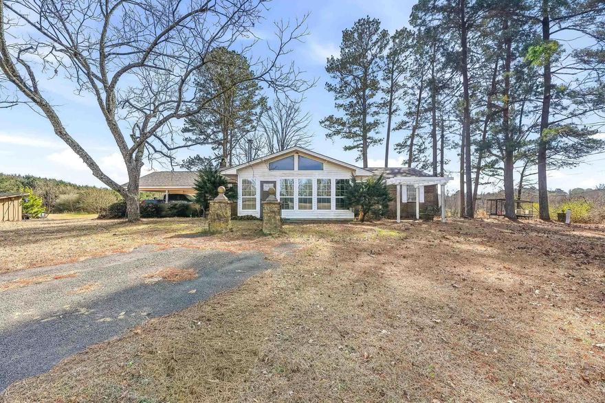 Welcome to peaceful country living on 25.25 acres in Lockesburg. This well-maintained four-bedroom, two-bath home offers the space and comfort that rural buyers are looking for. Originally built in 1970, the home was fully remodeled in 2022 with updated flooring, fresh paint, new countertops, and modern finishes throughout. The kitchen has been updated and plumbed for a future gas stove, and the home features a gas furnace, central heat and air, and a tankless hot water heater. The living room offers a warm, inviting space with cathedral ceilings and a wood-burning stove, plus an additional wood stove in the mudroom and gas logs in the primary bedroom. Outside, the property is set up and ready for livestock with 25.25 acres of pasture, fencing and cross-fencing, two barns, a workshop with awning, storage building, and a covered cattle working pen with head chute. A paved driveway leads to a two-car carport, and the property includes two working wells plus an additional well that only needs a pump. A new roof was installed in 2023.