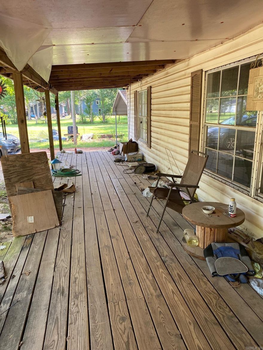 Three bedroom, two baths, double carport, front porch with bonus room, and wood back deck manufactured home on 0.49 acre lot.  House sits down driveway between 604 and 606 Mt. Holly Street in Smackover, AR.