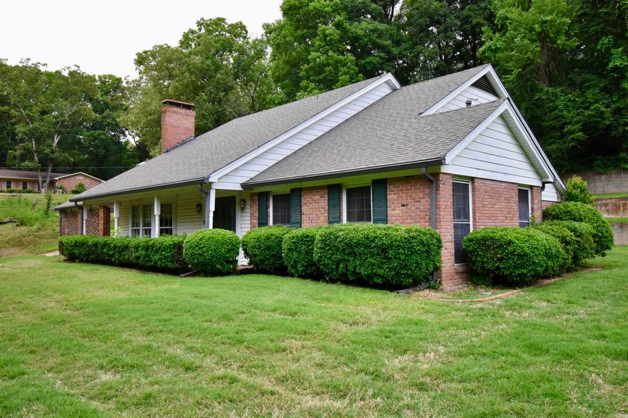 Nestled on approximately 3 private acres across three parcels, this spacious 3BR/3BA traditional home features beautiful outdoor space and a lighted tennis court on an adjoining lot. Surrounded by mature trees and a well-maintained lawn, the property provides a peaceful setting with convenient accessibility. The front entry opens to a striking staircase and formal living room featuring hardwood floors, a gas fireplace, and large windows with abundant natural light. The formal dining room flows into the kitchen, complete with double ovens, electric cooktop, island, breakfast area, decorative fireplace, dishwasher, garbage disposal, and access to a lovely back patio overlooking the property. An inviting den/hearth room includes exposed ceiling beams, a wood-burning fireplace, wet bar, bay window, and access to a covered carport with ample storage. The main-level primary suite features floor-length bay windows, built-in bookshelves, walk-in closet, and ensuite bath. Upstairs offers two bright bedrooms, shared full bath, and floored attic storage. Generator included. A rare opportunity to own a multi-parcel property with acreage, recreational amenities, and classic Southern charm.
