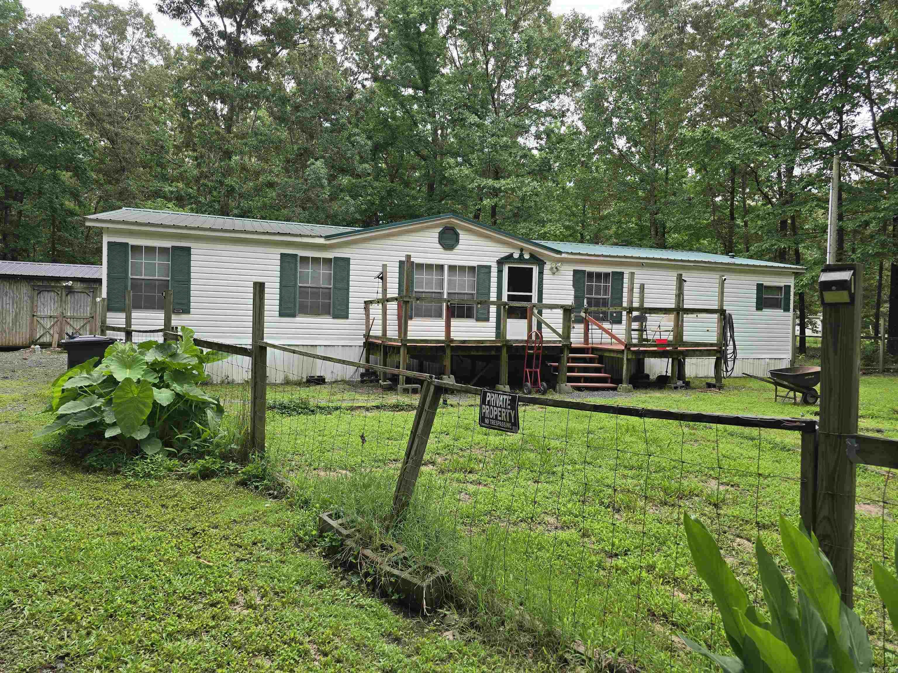 This spacious 3bed 2bath double wide is nestled in among mature hardwood trees on a private 3-acre lot outside of town. This all-electric home features an open floor plan with 2 large living areas, a wood burning fireplace, and dining area. The sizable kitchen has lots of cabinet and counter space for all your cooking needs. The master suite is also extremely spacious with a walk-in closet and master bath with double vanity, garden tub, and separate shower. The Heat and Air system is 3 years old. The property has 3 storage buildings, (the largest has electricity) its fully fenced with entry gate, a fire pit and much more. Come see this amazing property today!