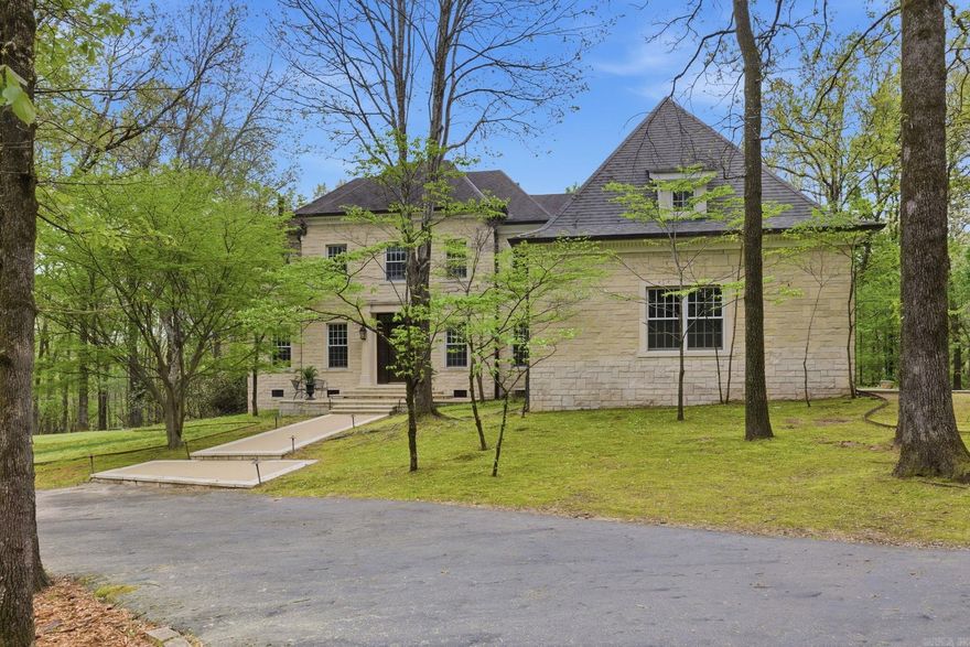 A rare offering of craftsmanship, this custom-built gated estate rests gracefully on 10 secluded, wooded acres—designed as a true forever home. The natural Batesville, AR limestone exterior sets a timeless tone. Inside, rich hardwood floors flow throughout the main living spaces, complemented by a thoughtfully designed kitchen featuring granite surfaces, a gas range, double ovens, generous storage, and a walk-in pantry. The main level offers a refined dining room, a sophisticated front office, a formal living room, and an inviting great room that anchors the heart of the home. The main level primary suite offers a private retreat, while the upper level expands the home’s versatility with three spacious bedrooms, each with bath access, an additional office/flex space opening to a covered upper patio, and a vaulted bonus room ideal for entertaining. Outdoors, the estate unfolds into a peaceful sanctuary with an inground Gunite pool surrounded by mature trees and natural beauty. The three-car garage offers private parking. Perfectly positioned with convenient access to Chenal’s shopping and dining, yet worlds away in feel—this is a legacy property built to be enjoyed for generations.