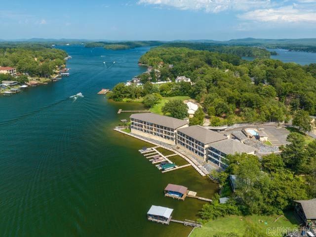 No Stairs, Just Views — Ground-Level on Lake Hamilton with a Boat Slip! Located in the Hwy 7 South area, this walk-in level condo offers comfortable lakefront living with great water views. The open-concept living, dining, and kitchen area includes a wet bar and an electric fireplace, creating a functional and inviting space. The primary ensuite features a large walk-in closet and direct access to the covered patio—an ideal spot to watch sunsets and holiday fireworks. This unit is offered complete with tasteful furnishings and includes a Boat Slip. Additional amenities include one covered, assigned parking space directly in front of the building, with additional parking nearby. Residents also enjoy access to a scenic boardwalk along the lake and a swimming pool. Short-Term Rentals are allowed, making this an ideal option for full-time living, a vacation getaway, or investment use.