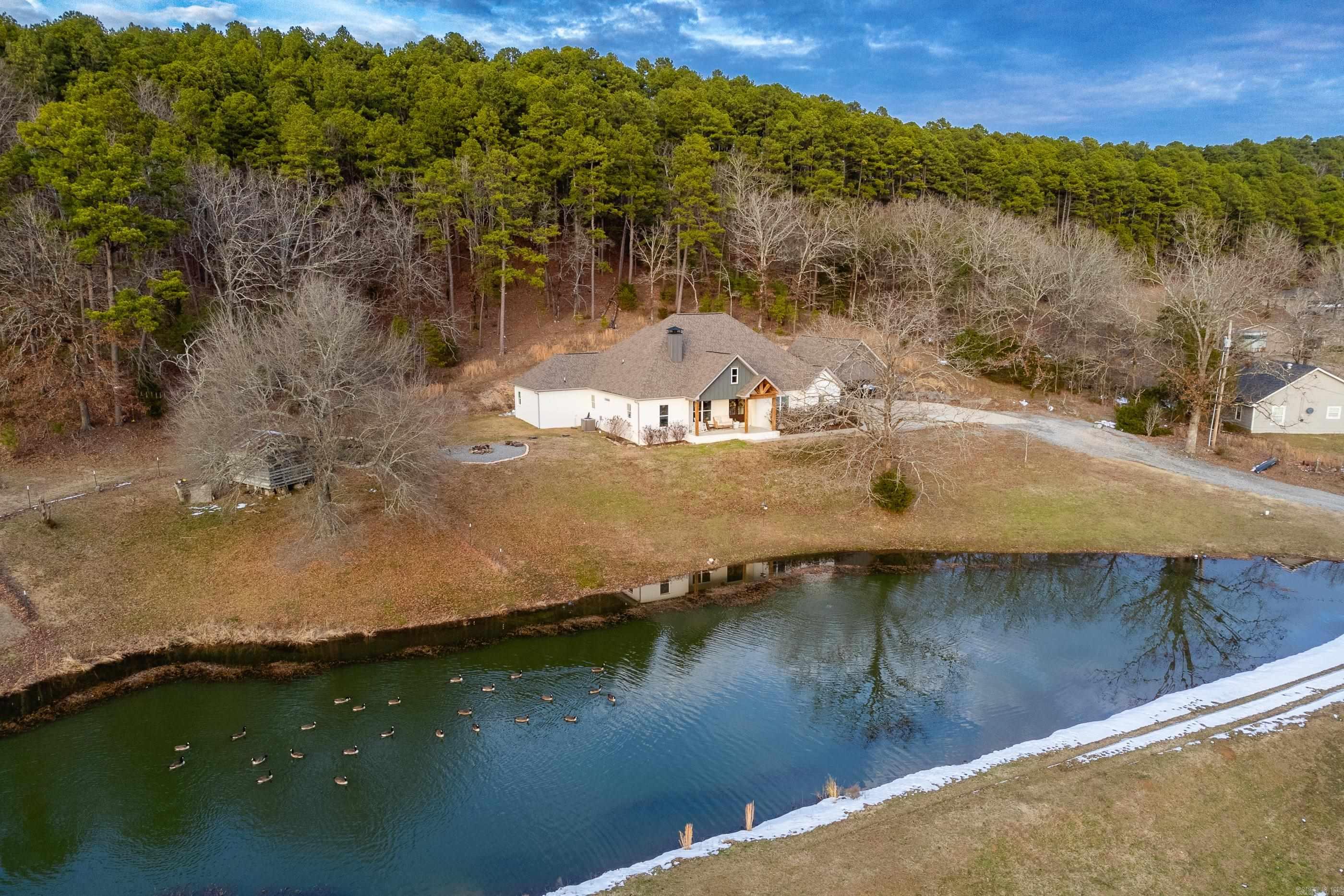 Located on over 9+ acres complete with pond, shop, playground, and generator, this property offers privacy with a one level open floor plan. Durable Atroguard waterproof floors with a 100% natural wood fiber core. Versatile floor plan - 4 BR plus office, bonus or 5th BR. Cozy wood burning fireplace with vaulted exposed beam detail. Chef's kitchen - quartz countertops, breakfast bar island, GE Cafe 6 burner/griddle gas cooktop, double oven, farm sink, open shelving. Private primary suite, recessed lighting, tile shower, connecting large closet to oversized laundry room with utility sink. Convenient mud room off covered back patio. One bedroom has en-suite bath; double sinks in 3rd bath. Come watch the Canadian geese from the front porch in the pond stocked with catfish, big bass, and brim. Country living at it's finest!