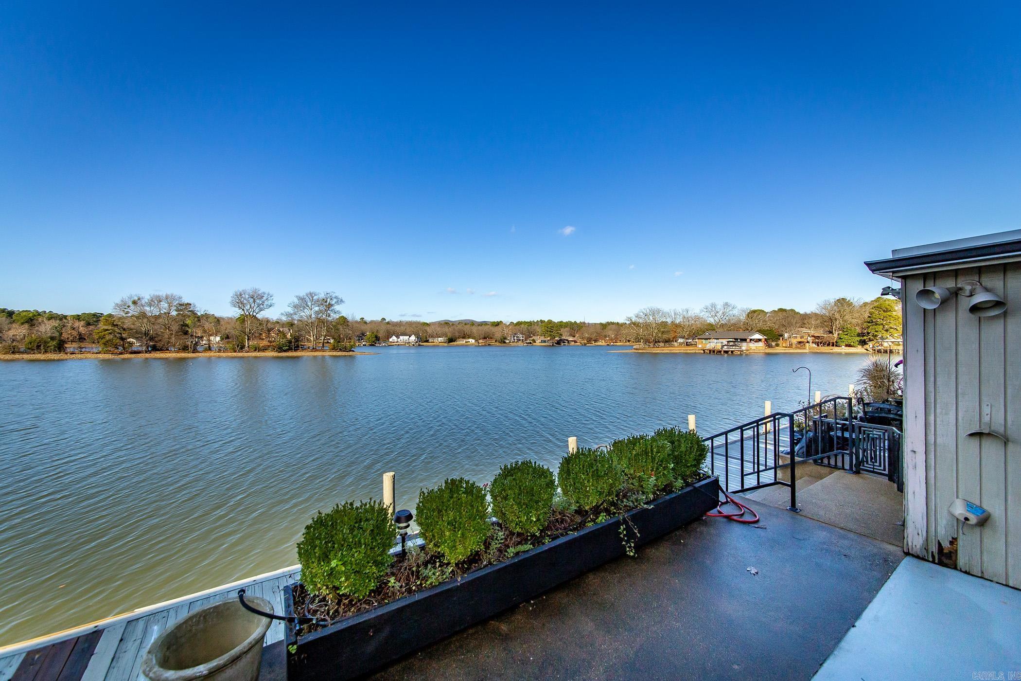 Coveted, gated Moonlight Bay Condominium located on the shores of Lake Hamilton. Experience waterfront living in this beautiful, updated 2 bedroom, 2.5 bath condo and enjoy the breathtaking, panoramic lakefront views from the den, covered patio and master bedroom. Updates include custom window treatments, quartz counters, lighting, and white oak floors, new dishwasher, new hot water heater, replaced front window. There are two large outside storage rooms on the patio. This convenient location in the heart of Lake Hamilton is just minutes away from downtown Hot Springs, Oaklawn, restaurants, shopping and entertainment venues for the entire family. This a perfect blend of lake living and enjoying what Hot Springs has to offer. Private boat ramp located on property. No nightly rentals. See Agent Remarks.
