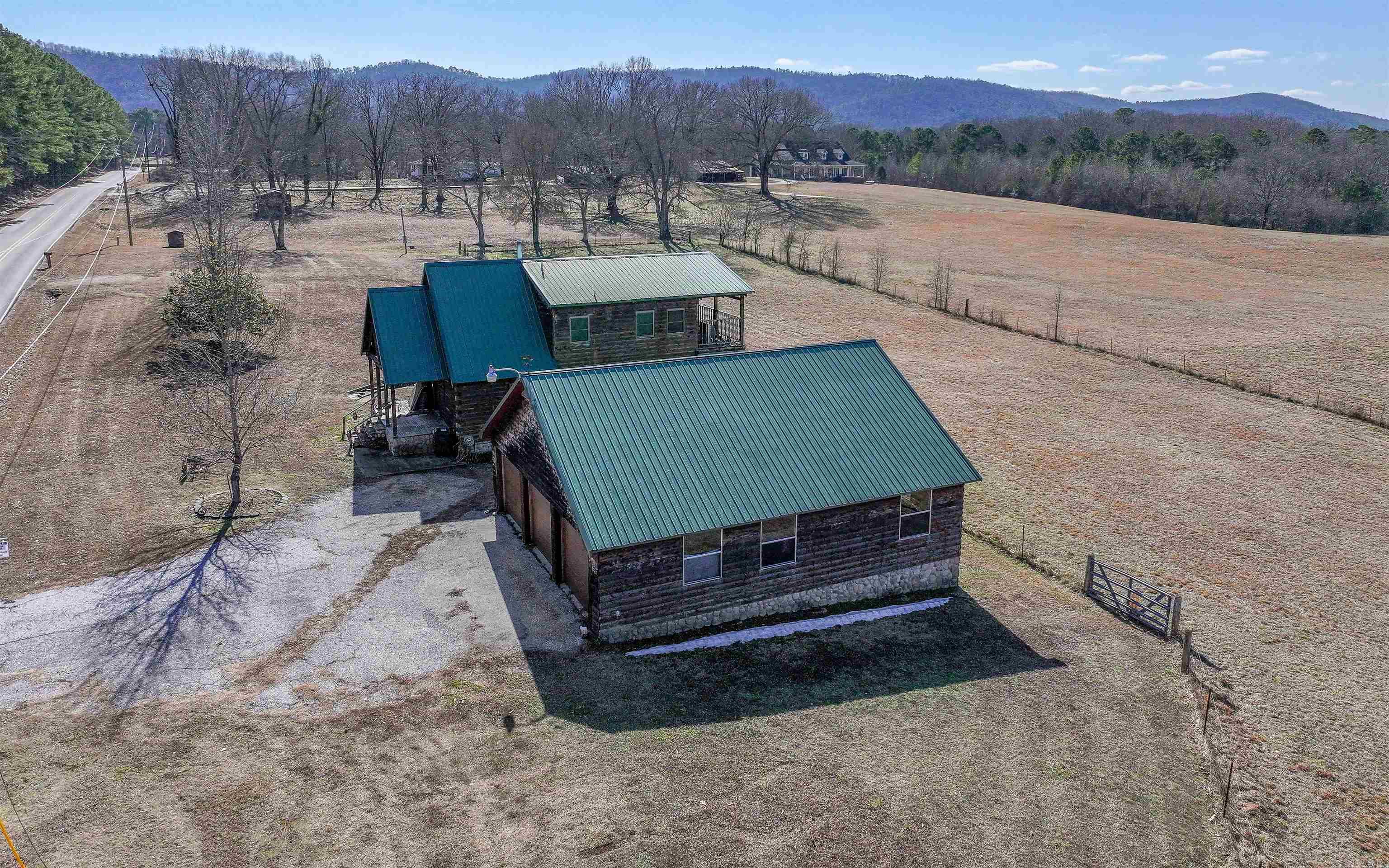 Clean air and blue skies are awaiting! Just minutes from the lake! This charming log-cabin style farmhouse sitting on 2 serene acres (MOL) in beautiful Hot Springs is just down the road from several horse farms in the Lake Hamilton School District! You will love the authenticity, quality, & custom features through-out. This cabin has been revived with new electrical and plumbing features including new lighting fixtures, new wiring, and new pipes. The kitchen has all new cabinetry, new granite countertops, and new appliances! The approximately 10-year-old metal roof has been professionally inspected & found to be in great condition. Both bathrooms feature custom-roomy showers of a stone & tile combination Cedar walls, vaulted wood ceiling with beams, & a woodstove give a cozy rustic feel. Downstairs has 2 bedrooms, a full bath, laundry area, and welcoming living area. Upstairs invites you into an approx. 250 sqft loft with full size bath. Step out the loft door to an expansive deck with scenic views of nearby farmland and mountains. The approx. 1440 sqft detached garage with matching log exterior has room for all your toys & tinkering. This one is ready for your finishing touches!