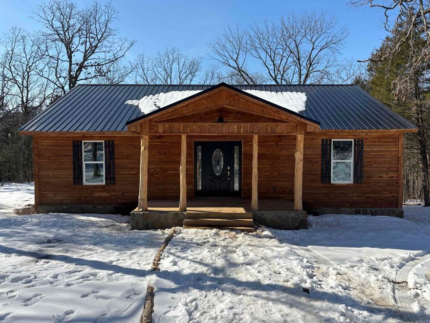 Welcome to this beautiful, newly constructed home featuring a cedar wood exterior that showcases rustic appeal and natural durability. The property boasts a metal roof, stone foundation accents and a covered front porch supported by natural log posts, creating a warm and inviting entrance. Step inside to the continued cozy feel of rustic accents including cedar covered ceiling and polished wood floors. A vaulted ceiling and recessed lighting create an inviting, spacious atmosphere. Kitchen is equipped with wood cabinetry and granite countertops, along with stainless steel appliances. Step outside to the covered back deck for your own private retreat to enjoy natures natural surroundings. Plenty of room on this back deck for grilling and entertaining!