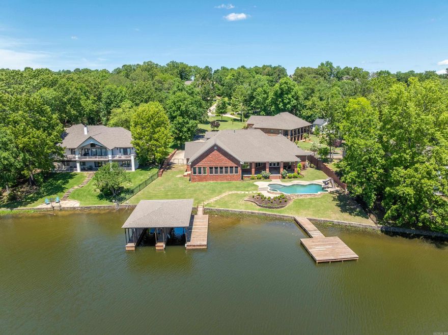 Custom Lake House on Lake Hamilton - A Waterfront Dream Home Discover an extraordinary custom-built lake house, perfectlypositioned on the serene shores of Lake Hamilton. This remarkable property spans 0.66 acres with an impressive 154 feet of lakefrontage, offering unparalleled views and direct access to the water. Spacious Living: With over 4,600 sq ft of living space, this homefeatures 5 bedrooms and 4 bathrooms, providing ample room for family and guests. Gourmet Kitchen: The large gourmet kitchen is achef’s dream, boasting top-of-the-line appliances, custom cabinetry, and expansive countertops—ideal for preparing meals andentertaining. Multiple Living Areas: Designed for comfort and versatility, the home includes multiple living areas, perfect for relaxing orhosting gatherings. Two cozy fireplaces add warmth and charm to the main living spaces. Primary Ensuite: The large primary ensuite isa true retreat, offering a luxurious bathroom and generous closet space. Outdoor Entertaining: The outdoor areas are an entertainer'sparadise, featuring a spacious screened-in porch, ample decking, and various spots to enjoy the lake views. Dive into the in-groundGunnite pool, complete with a